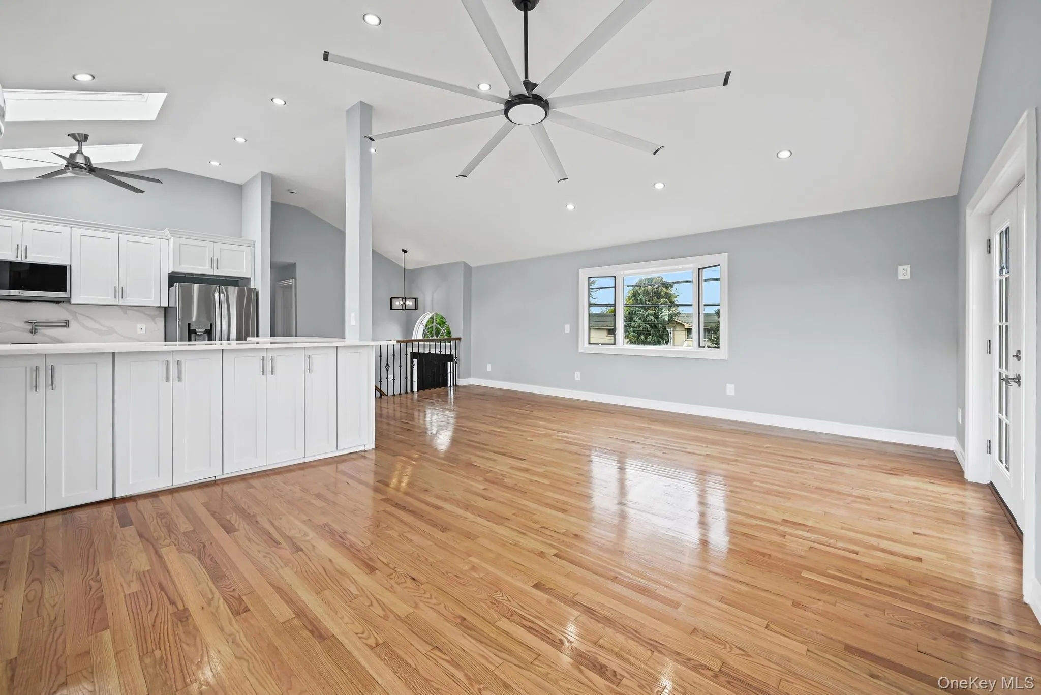 Unfurnished living room featuring a ceiling fan, light wood-style floors, a skylight, recessed lighting, and high vaulted ceiling Unfurnished living room featuring a ceiling fan, light wood-style floors, a skylight, recessed lighting, and high vaulted ceiling