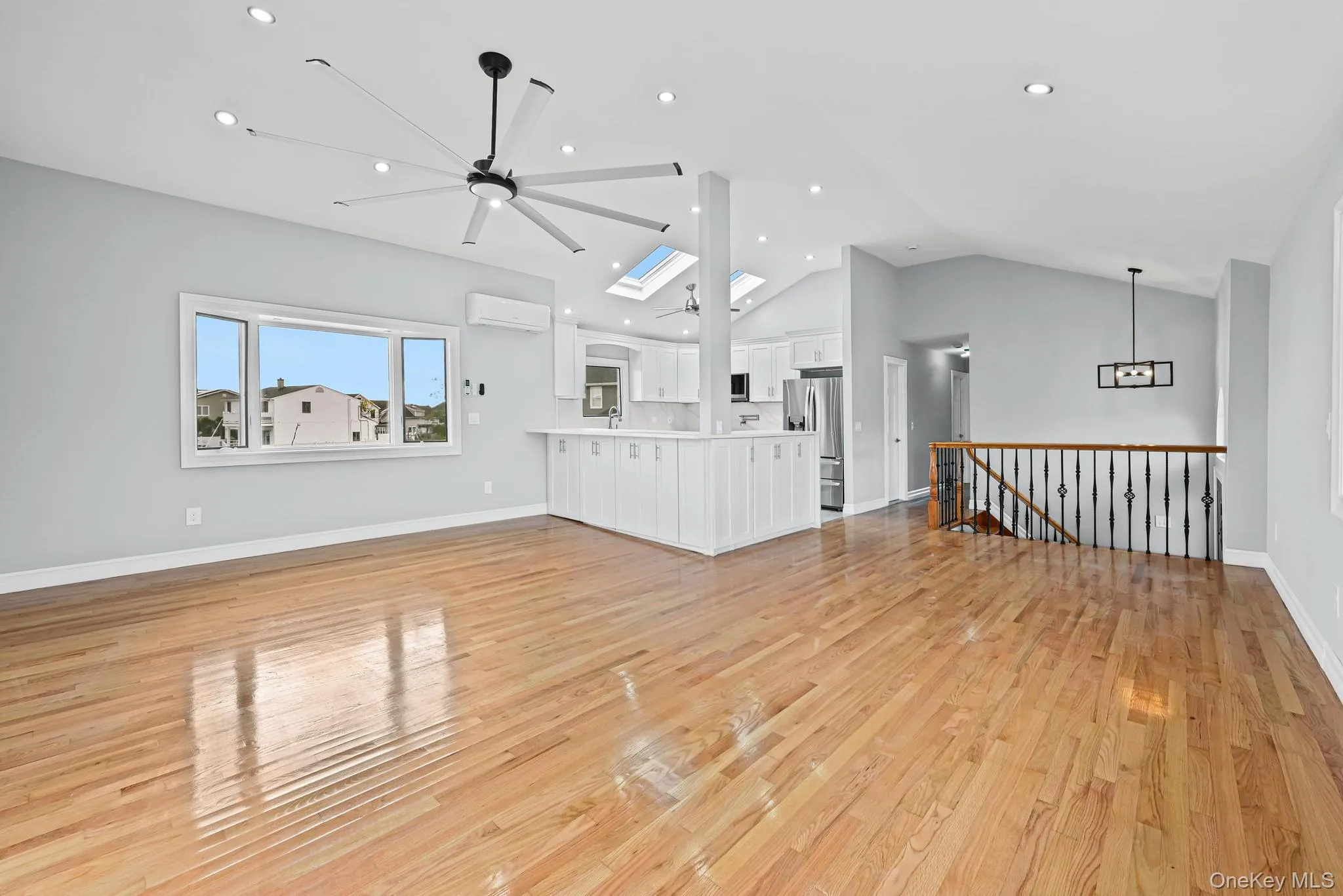 Unfurnished living room with light wood-type flooring, a skylight, vaulted ceiling, a ceiling fan, and recessed lighting Unfurnished living room with light wood-type flooring, a skylight, vaulted ceiling, a ceiling fan, and recessed lighting