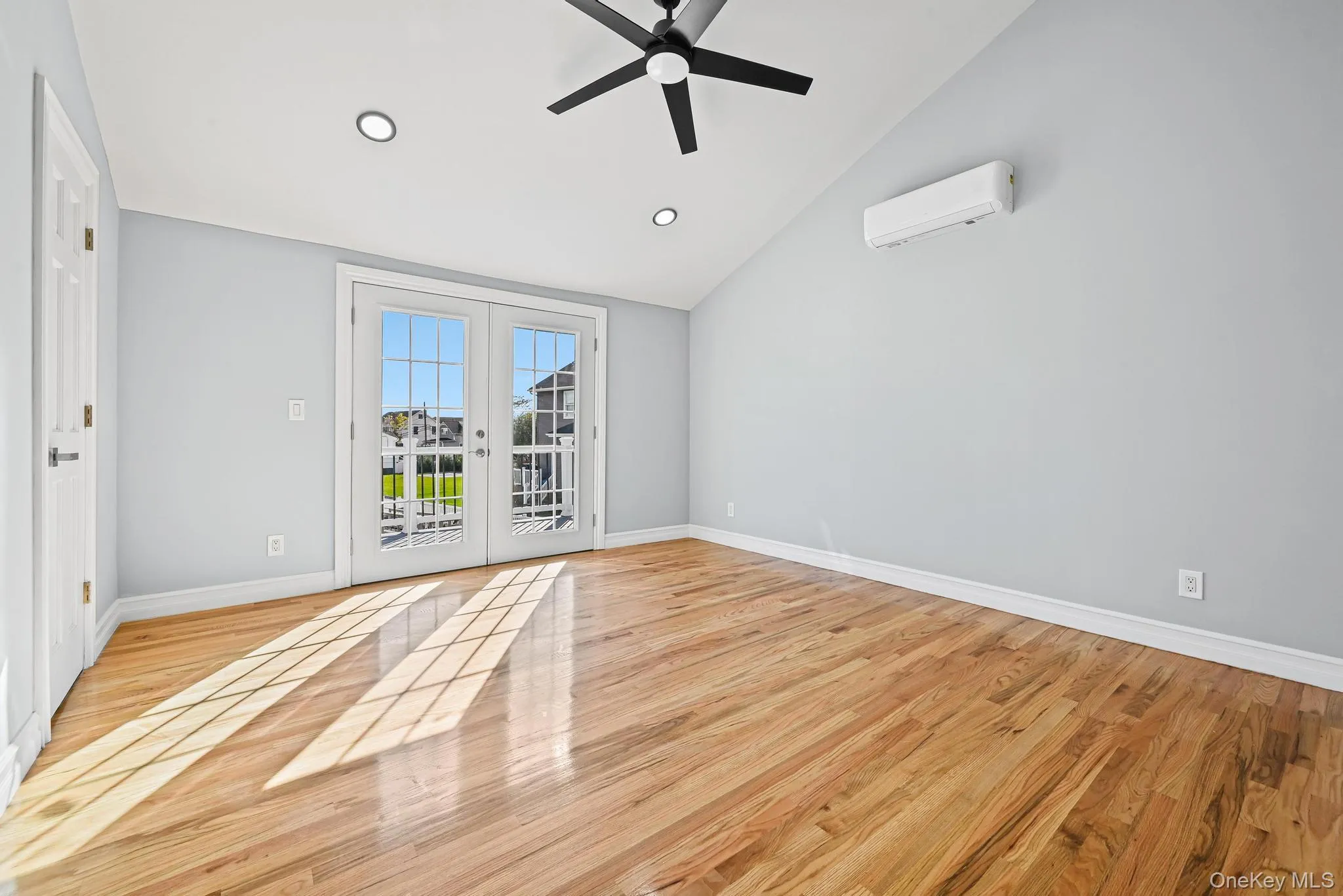 Spare room with french doors, a ceiling fan, light wood-type flooring, recessed lighting, and a wall mounted air conditioner Spare room with french doors, a ceiling fan, light wood-type flooring, recessed lighting, and a wall mounted air conditioner