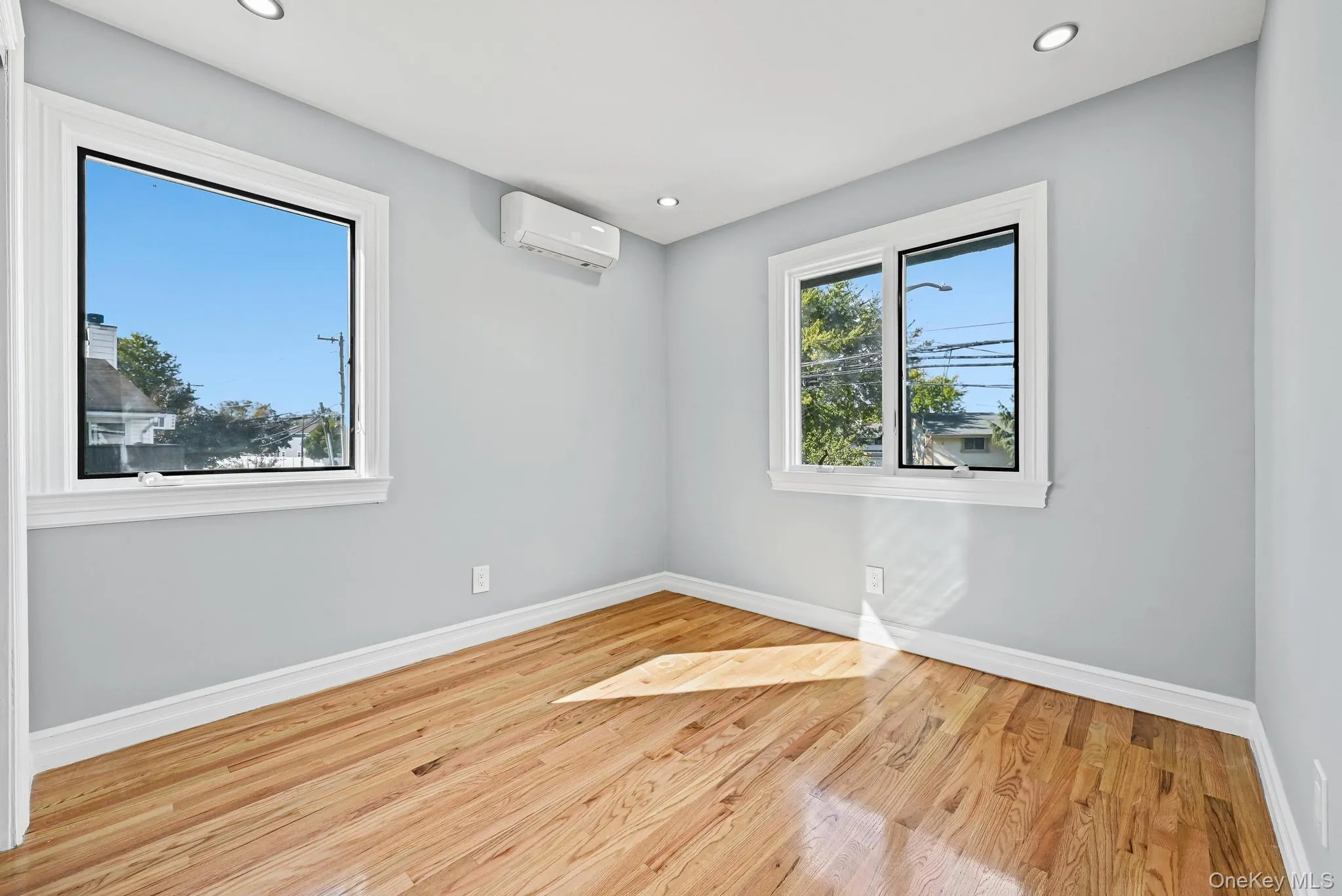 Empty room with light wood-style flooring, recessed lighting, and a wall mounted AC Empty room with light wood-style flooring, recessed lighting, and a wall mounted AC