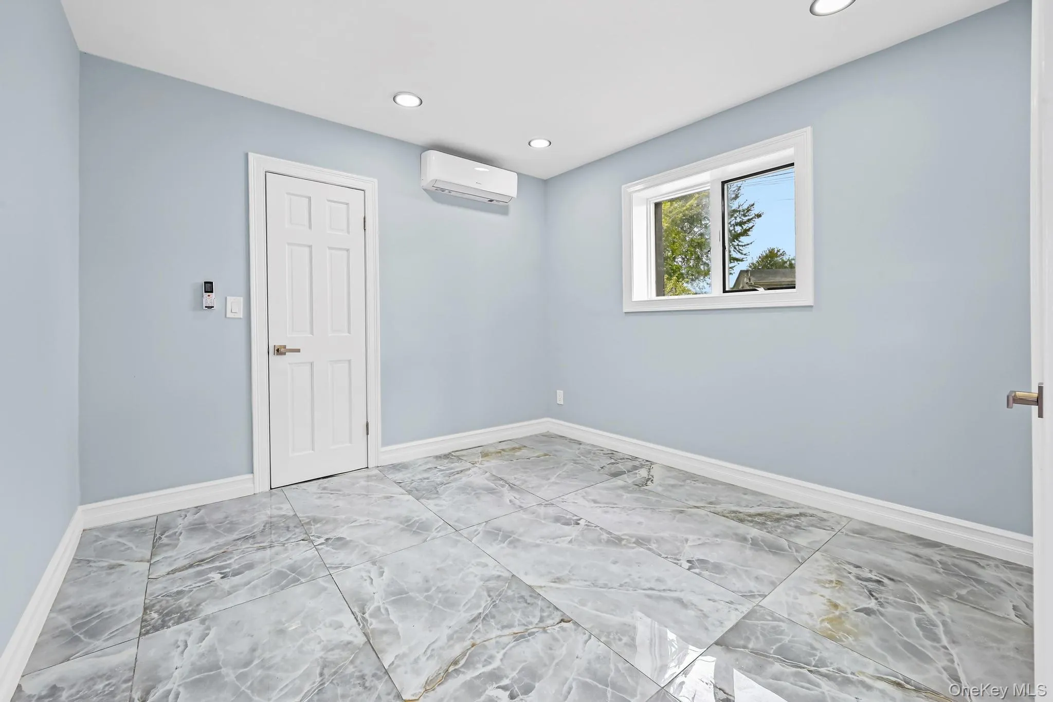 Empty room with light marble finish floors, recessed lighting, and a wall unit AC Empty room with light marble finish floors, recessed lighting, and a wall unit AC