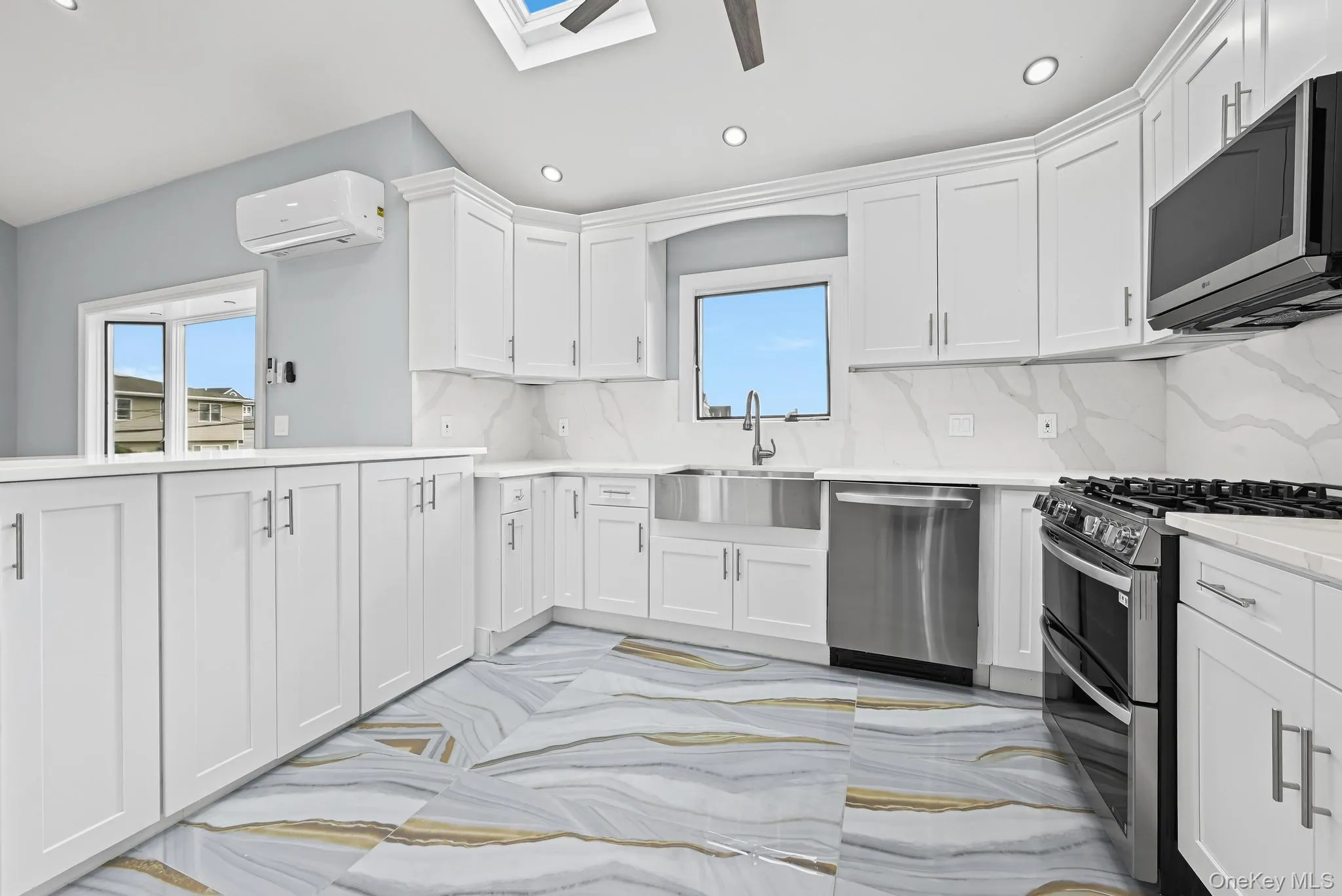 Kitchen with appliances with stainless steel finishes, white cabinets, tasteful backsplash, recessed lighting, and a skylight Kitchen with appliances with stainless steel finishes, white cabinets, tasteful backsplash, recessed lighting, and a skylight
