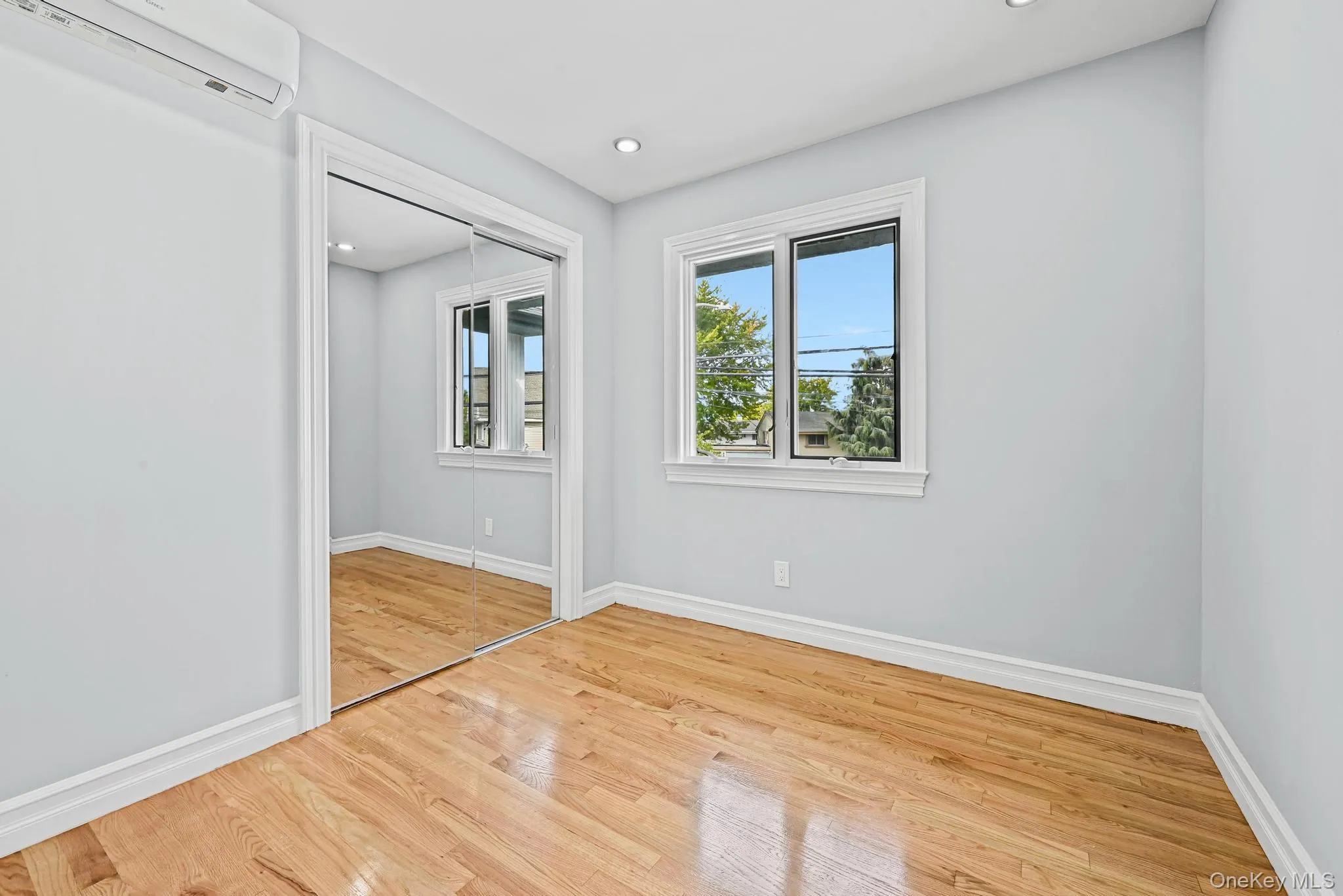 Unfurnished bedroom with an AC wall unit, light wood finished floors, a closet, and recessed lighting Unfurnished bedroom with an AC wall unit, light wood finished floors, a closet, and recessed lighting