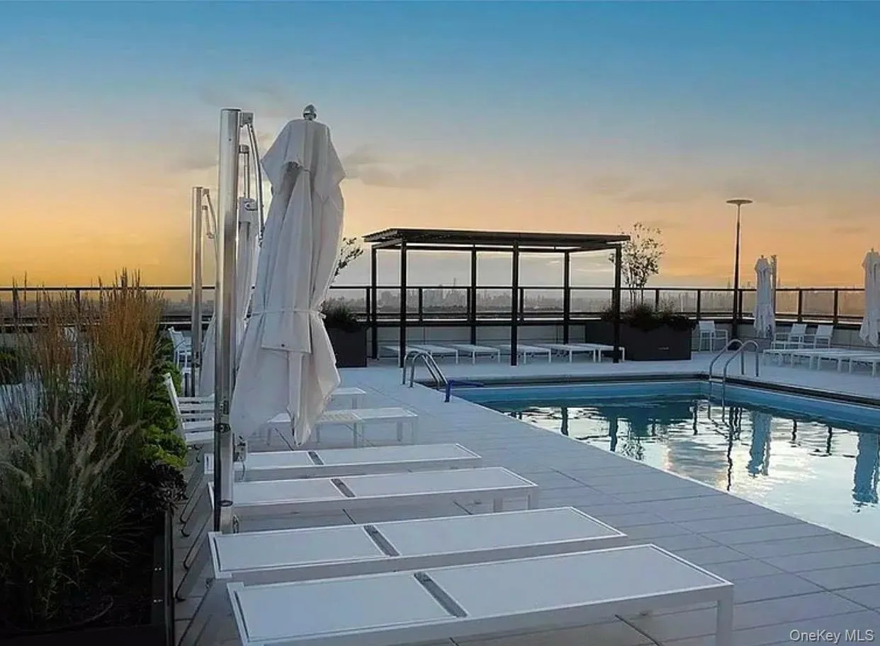 Rooftop pool deck featuring an in-ground swimming pool, multiple lounge chairs, and privacy screening Rooftop pool deck featuring an in-ground swimming pool, multiple lounge chairs, and privacy screening