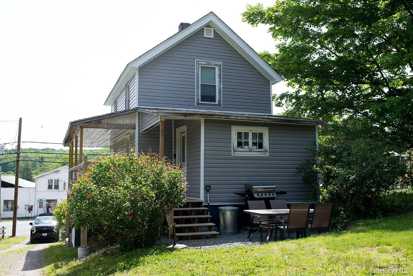 Three-story residence featuring grey horizontal siding and a covered porch Three-story residence featuring grey horizontal siding and a covered porch