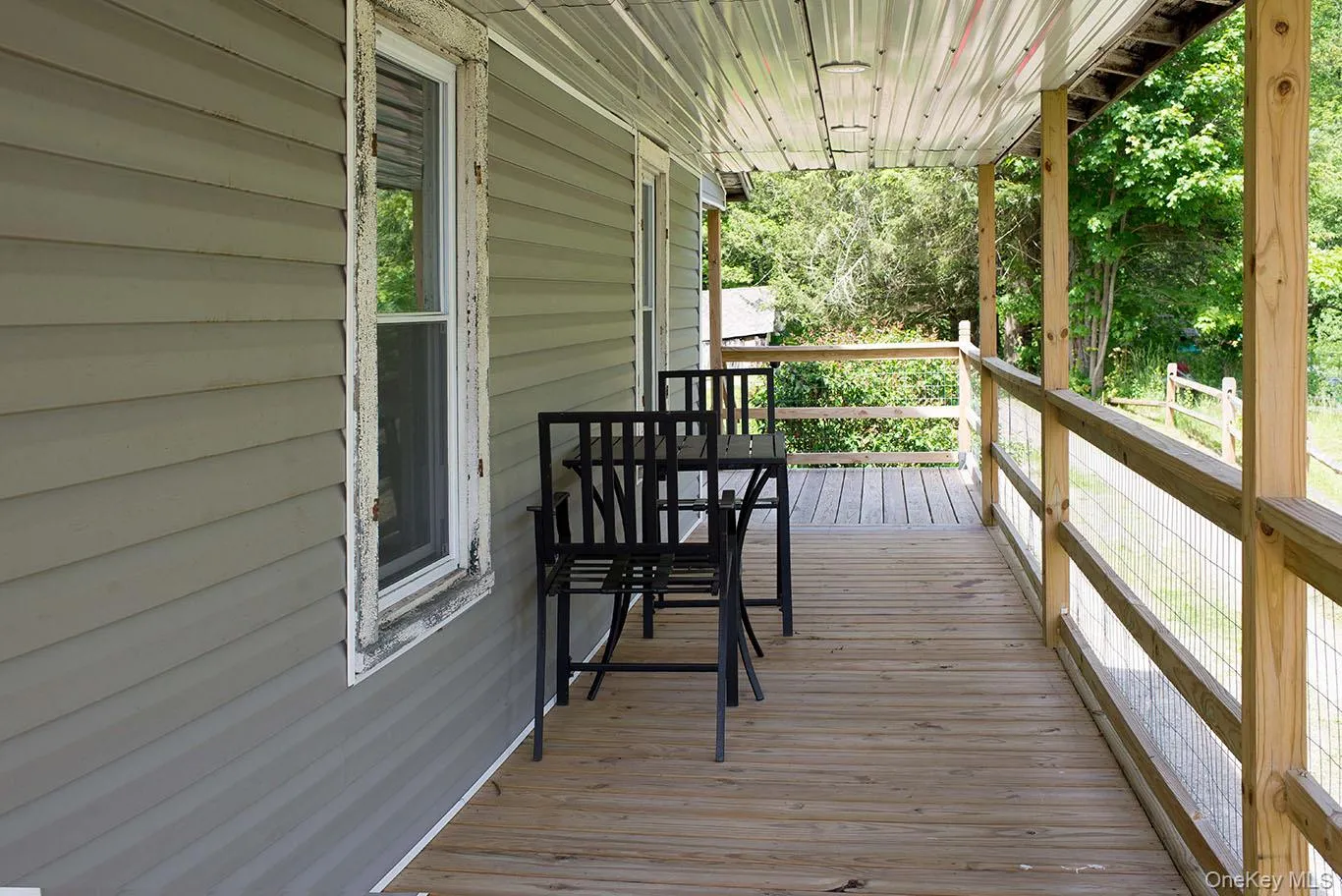 Inviting covered porch with natural wood plank flooring and wood railing Inviting covered porch with natural wood plank flooring and wood railing