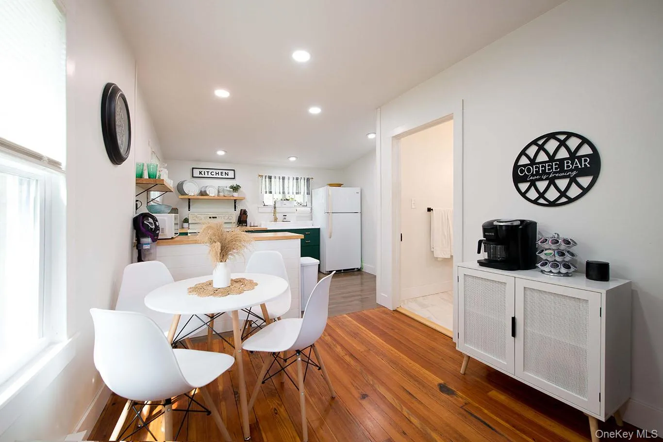 Open-concept living area featuring wood-finish flooring, recessed lighting, and a white color palette Open-concept living area featuring wood-finish flooring, recessed lighting, and a white color palette