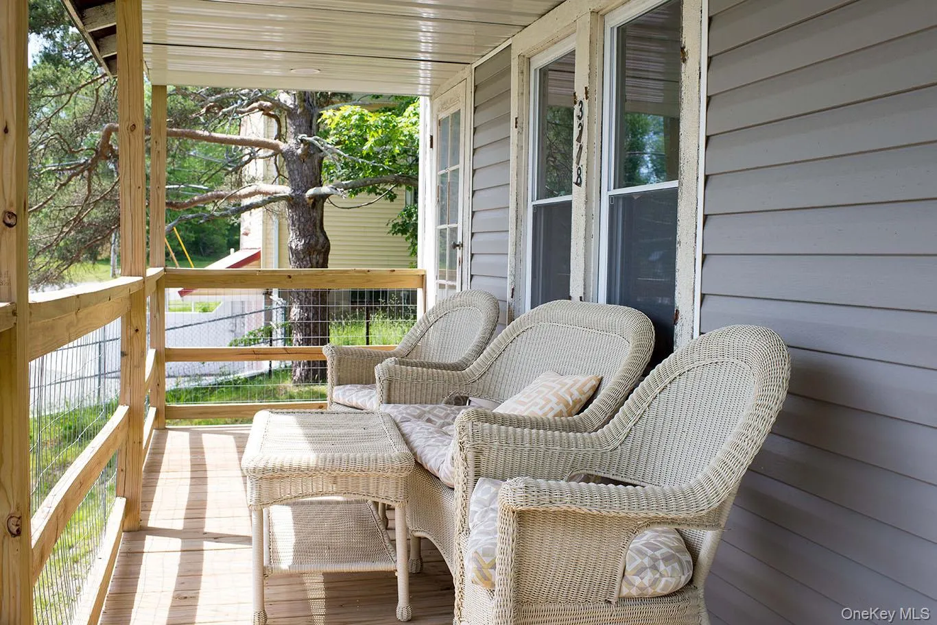Covered porch featuring wood plank flooring and natural wood railings Covered porch featuring wood plank flooring and natural wood railings
