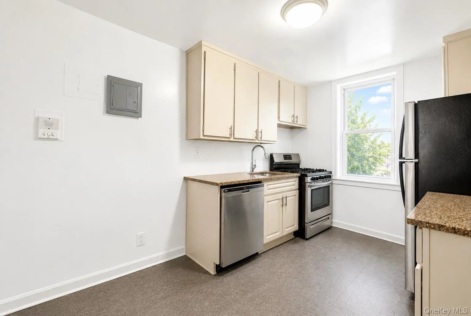Kitchen featuring light cabinetry, granite-finish countertops, and stainless steel appliances including a dishwasher and gas range Kitchen featuring light cabinetry, granite-finish countertops, and stainless steel appliances including a dishwasher and gas range