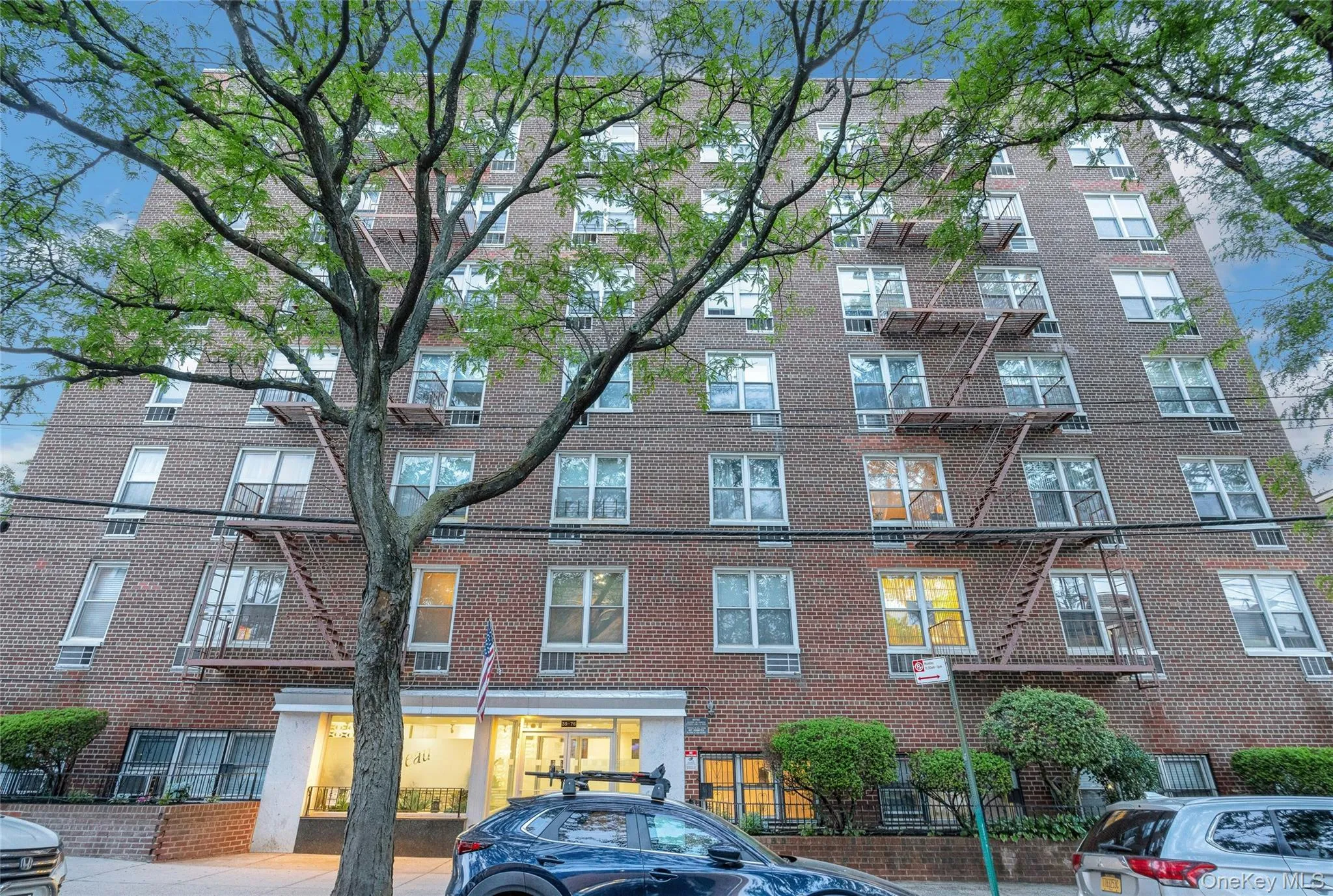 Brick facade building featuring multiple levels of windows, a prominent fire escape system, and a street-level entrance Brick facade building featuring multiple levels of windows, a prominent fire escape system, and a street-level entrance