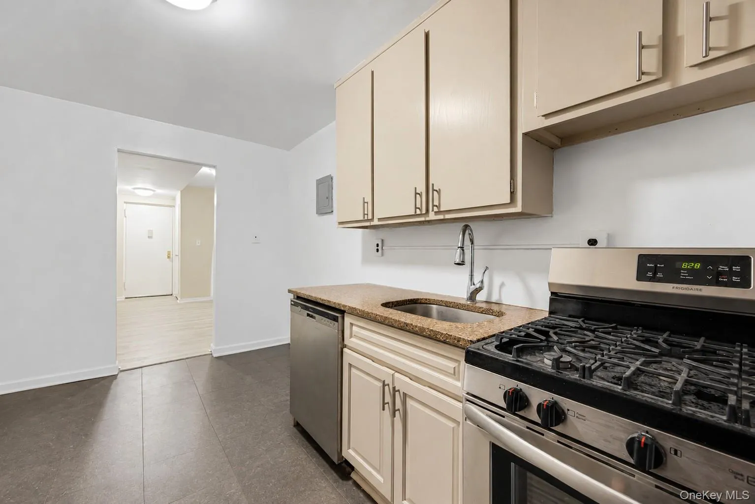 Kitchen featuring cream cabinetry, stainless steel gas range, stainless steel dishwasher, and a stone-finish countertop with an undermount sink Kitchen featuring cream cabinetry, stainless steel gas range, stainless steel dishwasher, and a stone-finish countertop with an undermount sink