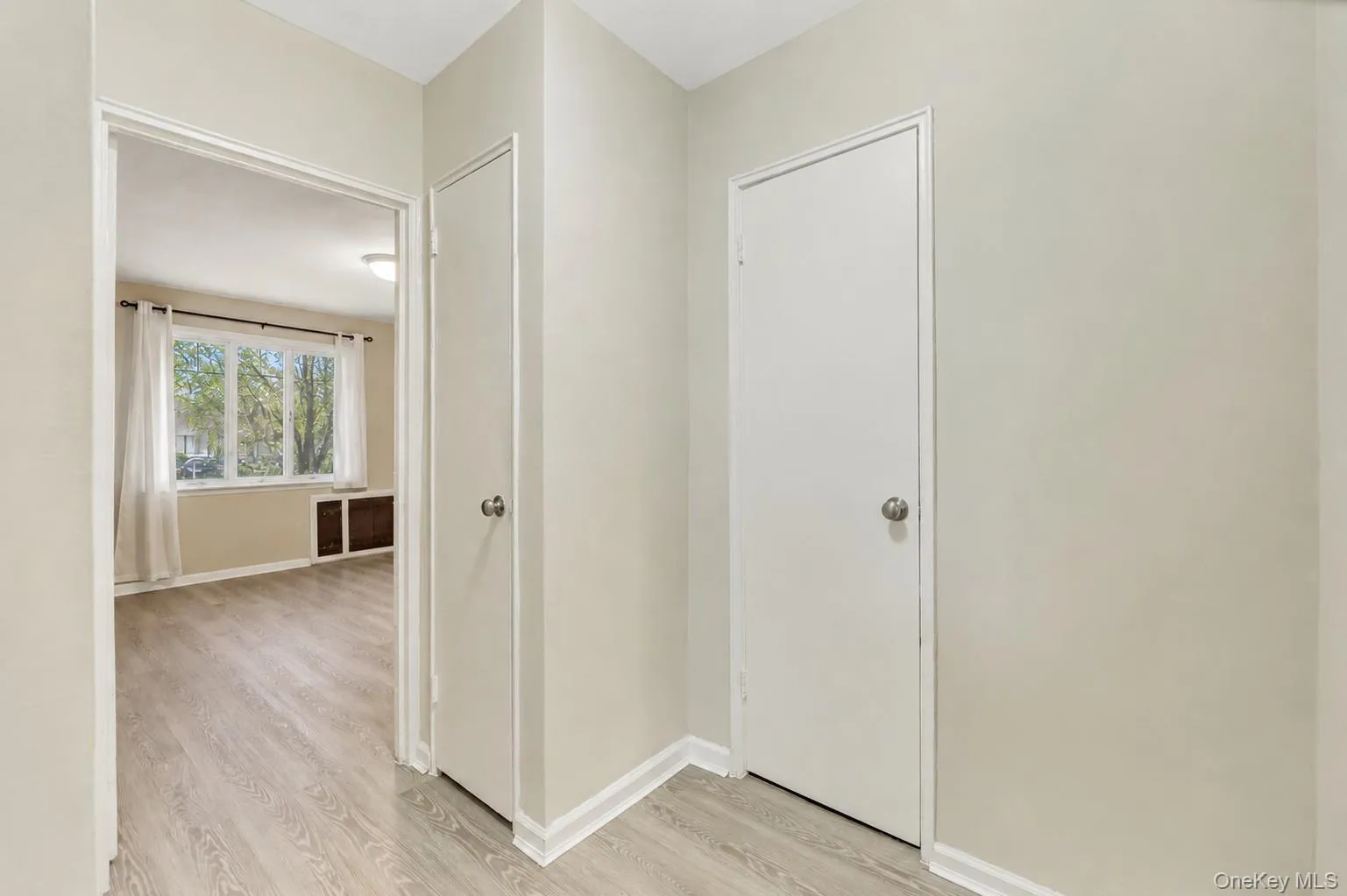 Interior hallway with light-toned walls and wood-finish flooring Interior hallway with light-toned walls and wood-finish flooring
