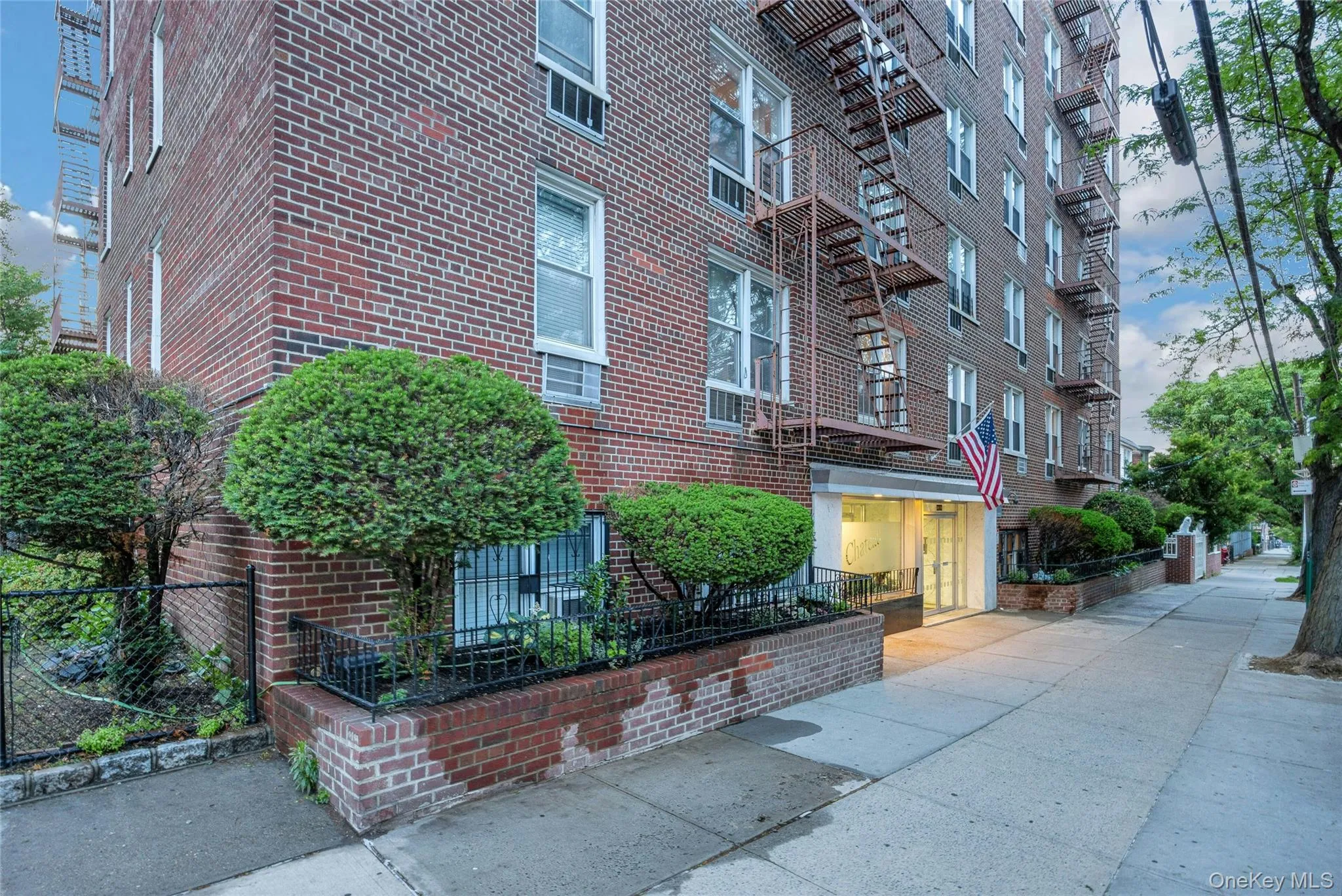 Brick exterior building featuring multiple windows, a prominent main entrance, and fire escape access Brick exterior building featuring multiple windows, a prominent main entrance, and fire escape access