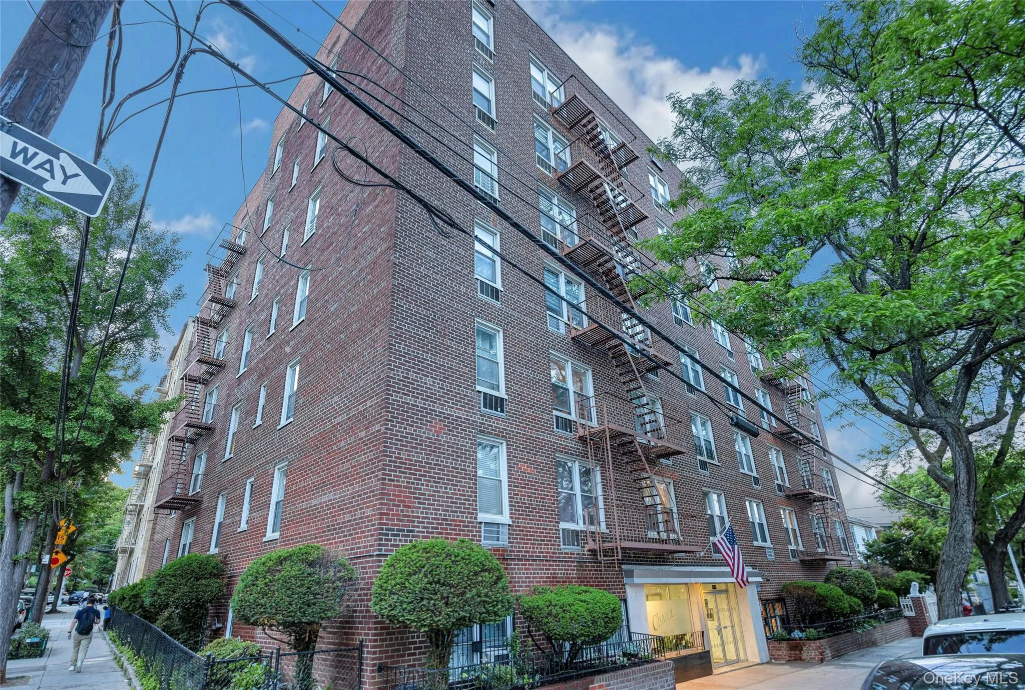 Brick multi-story building featuring multiple windows, a prominent fire escape system, and a recessed main entrance Brick multi-story building featuring multiple windows, a prominent fire escape system, and a recessed main entrance