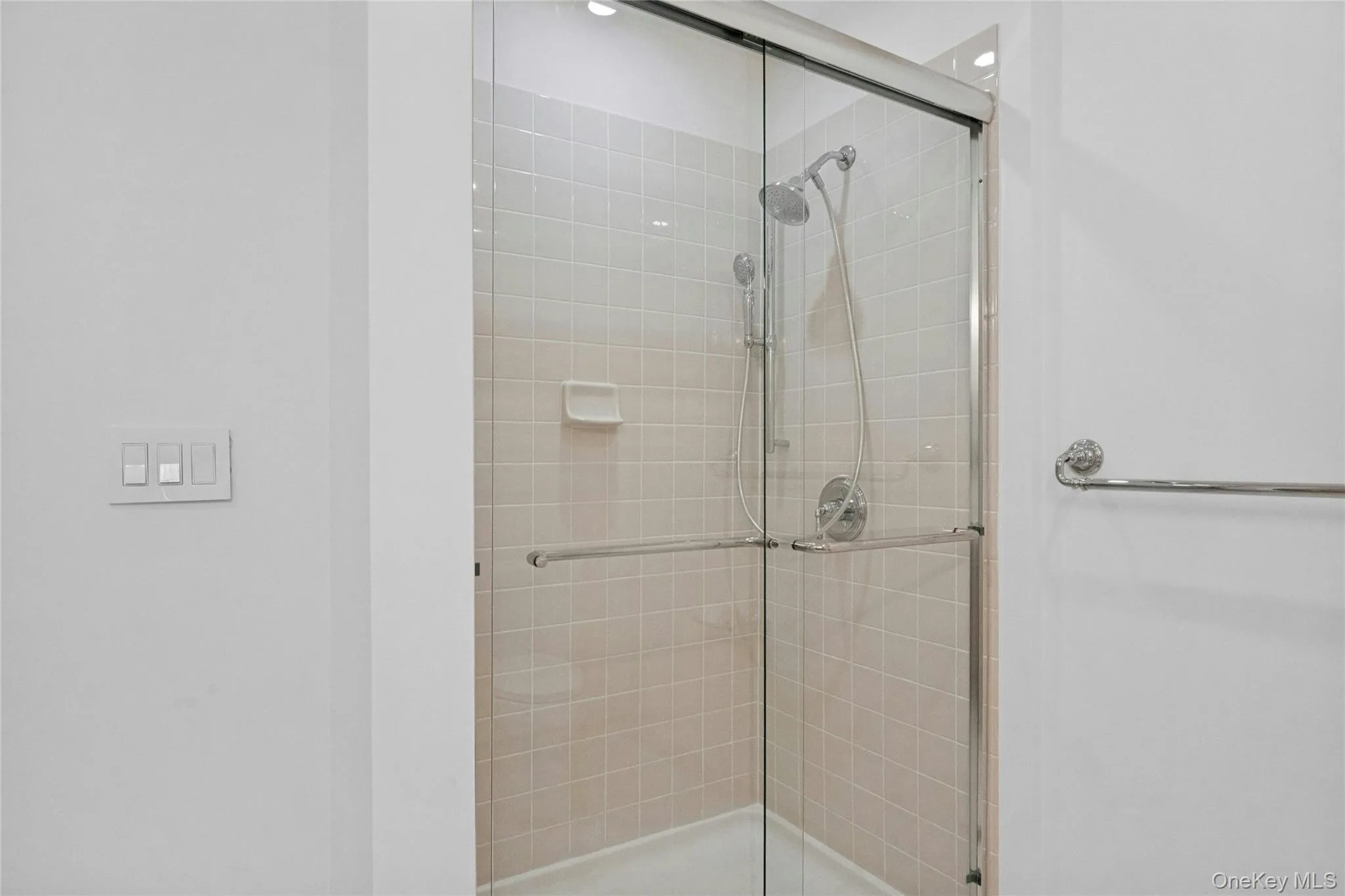Primary shower with new chrome fixtures, and a handheld shower head, and new glass doors Primary shower with new chrome fixtures, and a handheld shower head, and new glass doors
