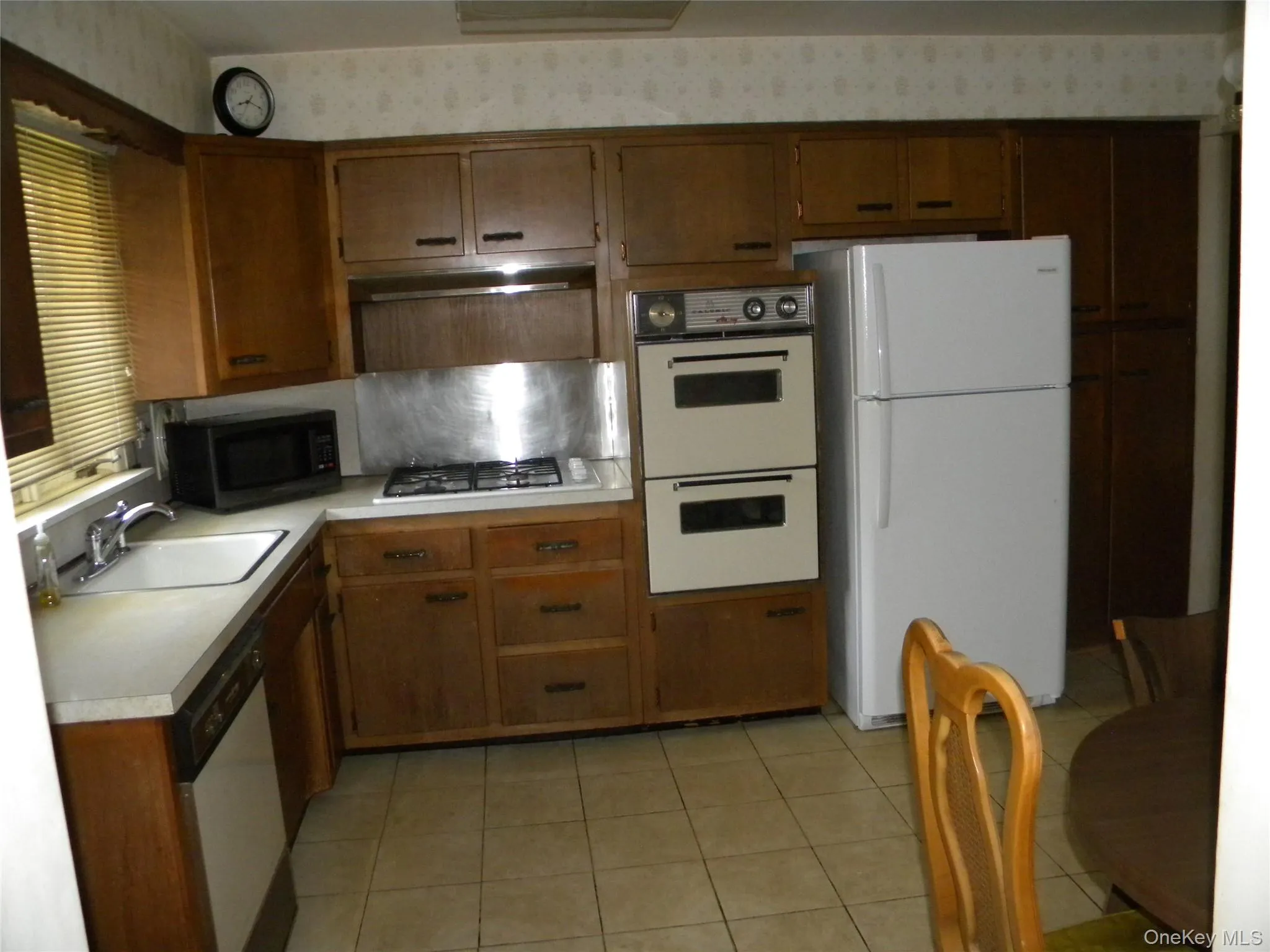 Kitchen featuring wood cabinetry, white countertops, built-in double ovens, and tile flooring Kitchen featuring wood cabinetry, white countertops, built-in double ovens, and tile flooring