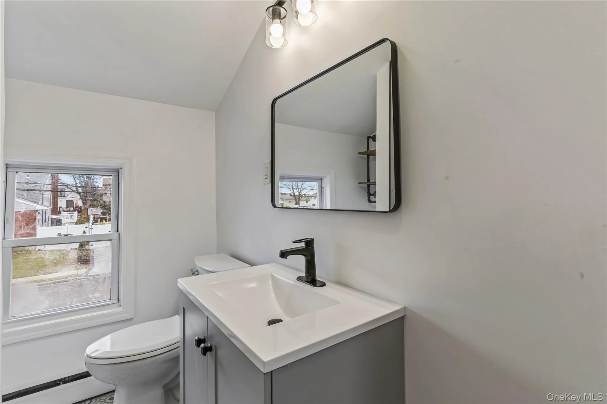 Bathroom featuring vanity, baseboard heating, and plenty of natural light Bathroom featuring vanity, baseboard heating, and plenty of natural light
