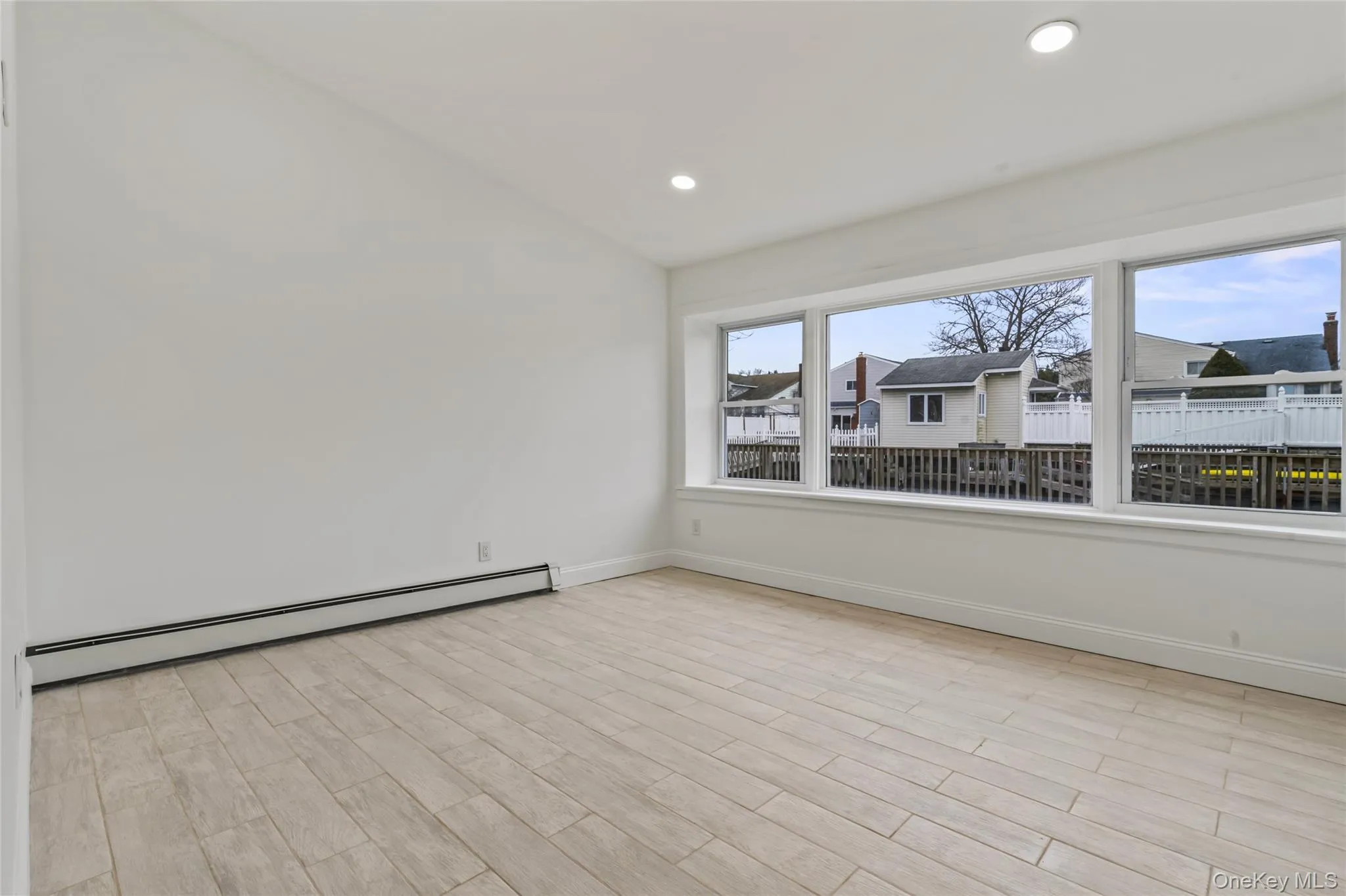 Unfurnished room featuring baseboard heating, wood finish floors, and recessed lighting Unfurnished room featuring baseboard heating, wood finish floors, and recessed lighting