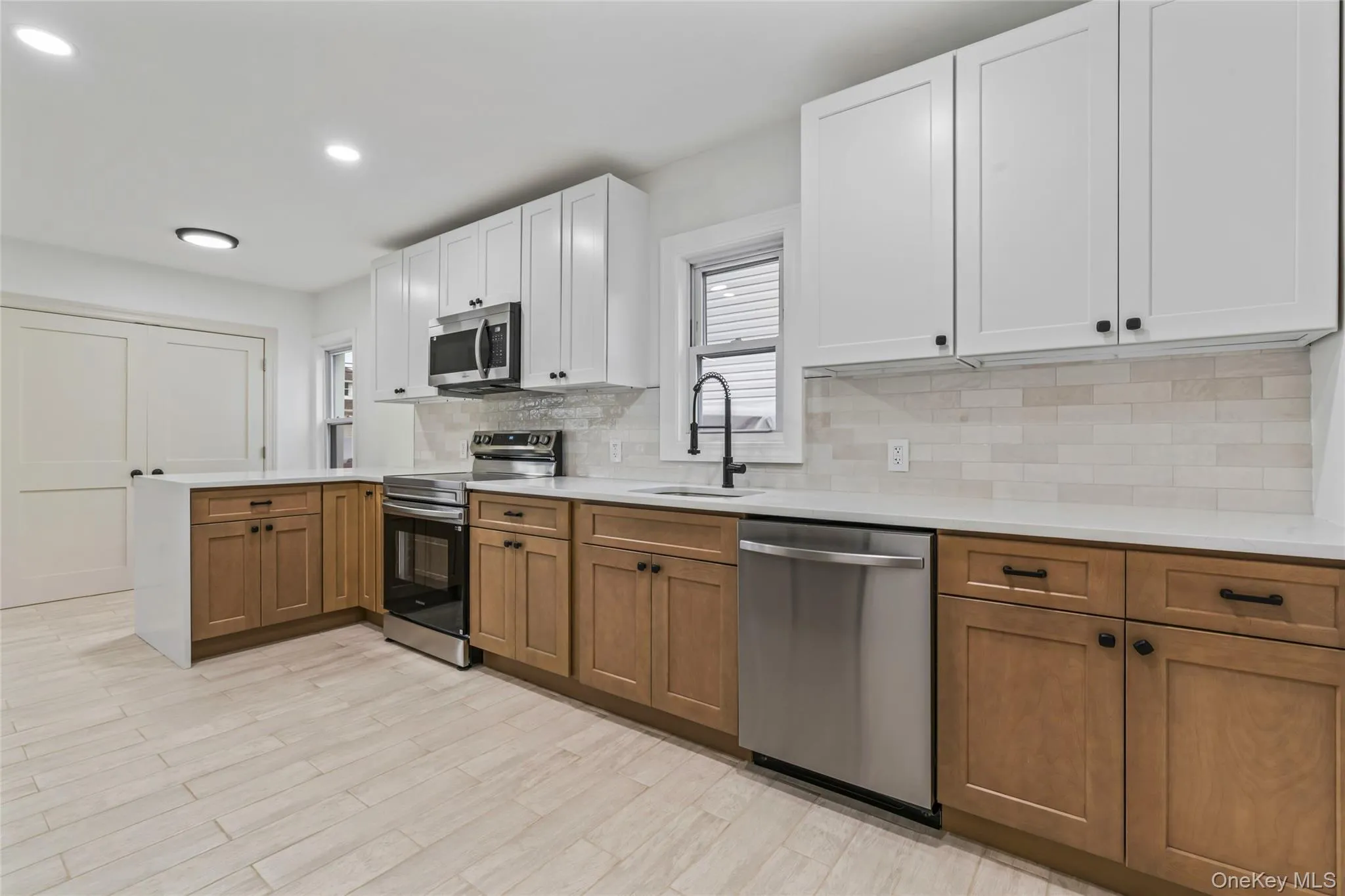 Kitchen with brown cabinetry, a peninsula, appliances with stainless steel finishes, plenty of natural light, and recessed lighting Kitchen with brown cabinetry, a peninsula, appliances with stainless steel finishes, plenty of natural light, and recessed lighting