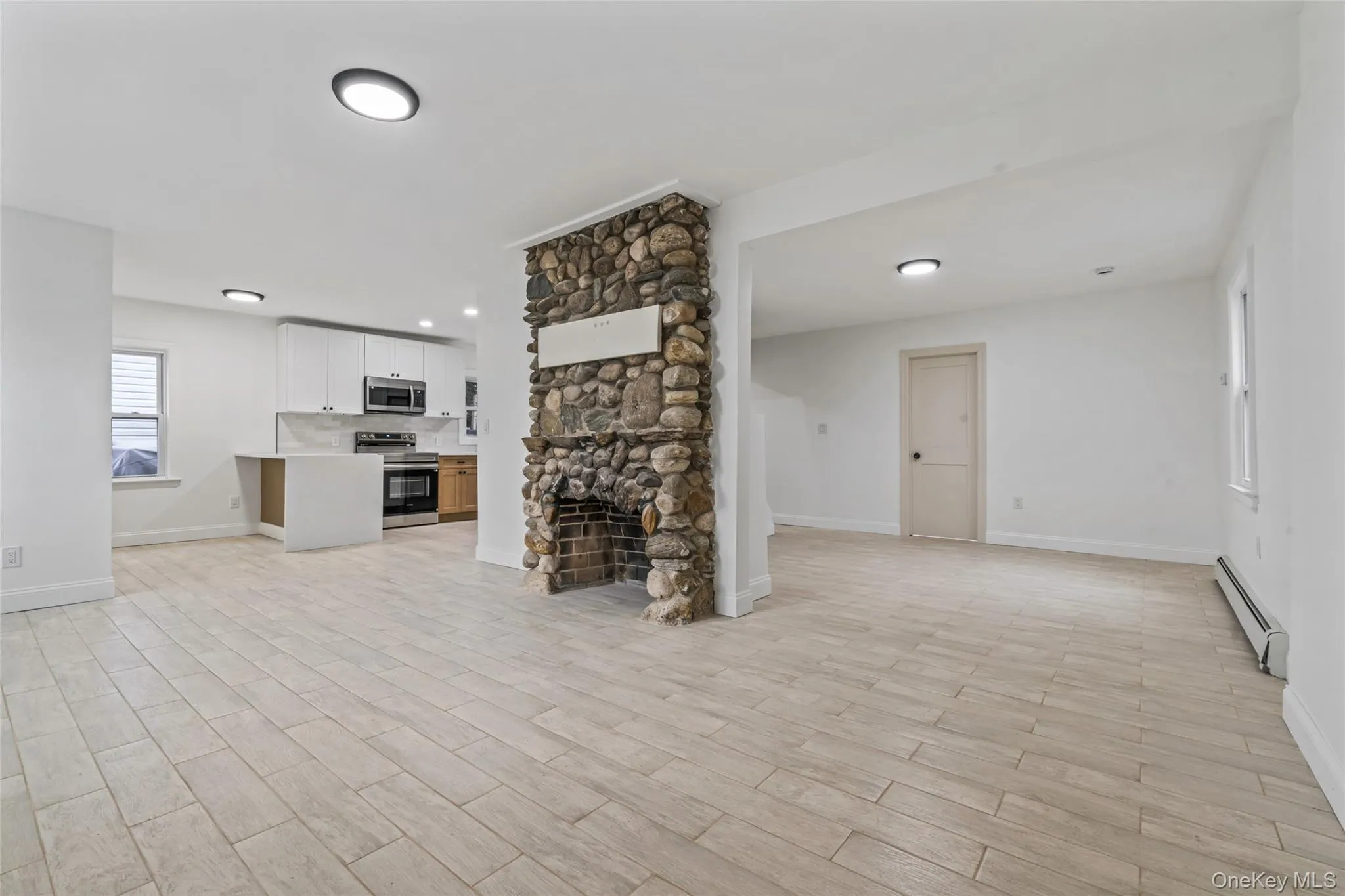 Unfurnished living room featuring a baseboard radiator, a fireplace, and wood tiled floors Unfurnished living room featuring a baseboard radiator, a fireplace, and wood tiled floors