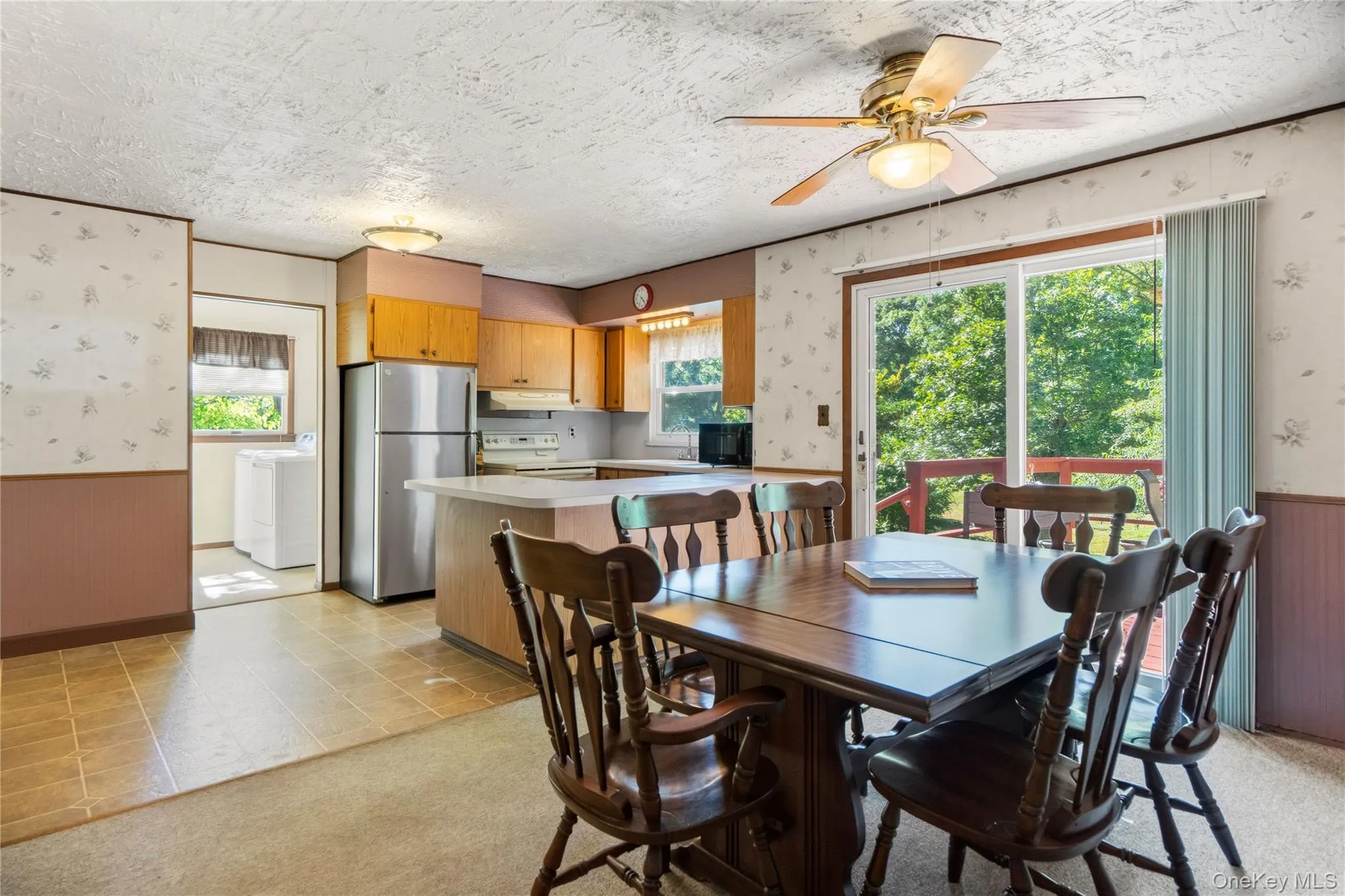 Eat-in kitchen featuring wood-finish cabinetry, stainless steel refrigerator, and a breakfast bar Eat-in kitchen featuring wood-finish cabinetry, stainless steel refrigerator, and a breakfast bar