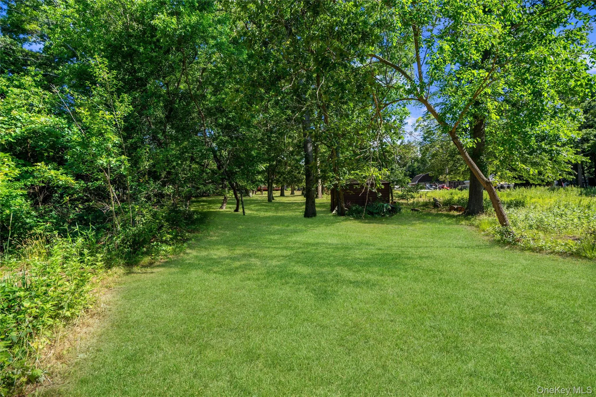 Expansive green lawn surrounded by mature trees, offering a private, natural setting Expansive green lawn surrounded by mature trees, offering a private, natural setting