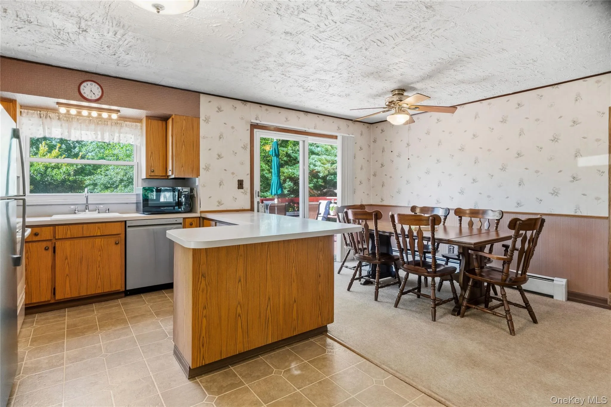 Kitchen and dining area featuring wood-finish cabinetry, stainless steel appliances, and a breakfast bar Kitchen and dining area featuring wood-finish cabinetry, stainless steel appliances, and a breakfast bar