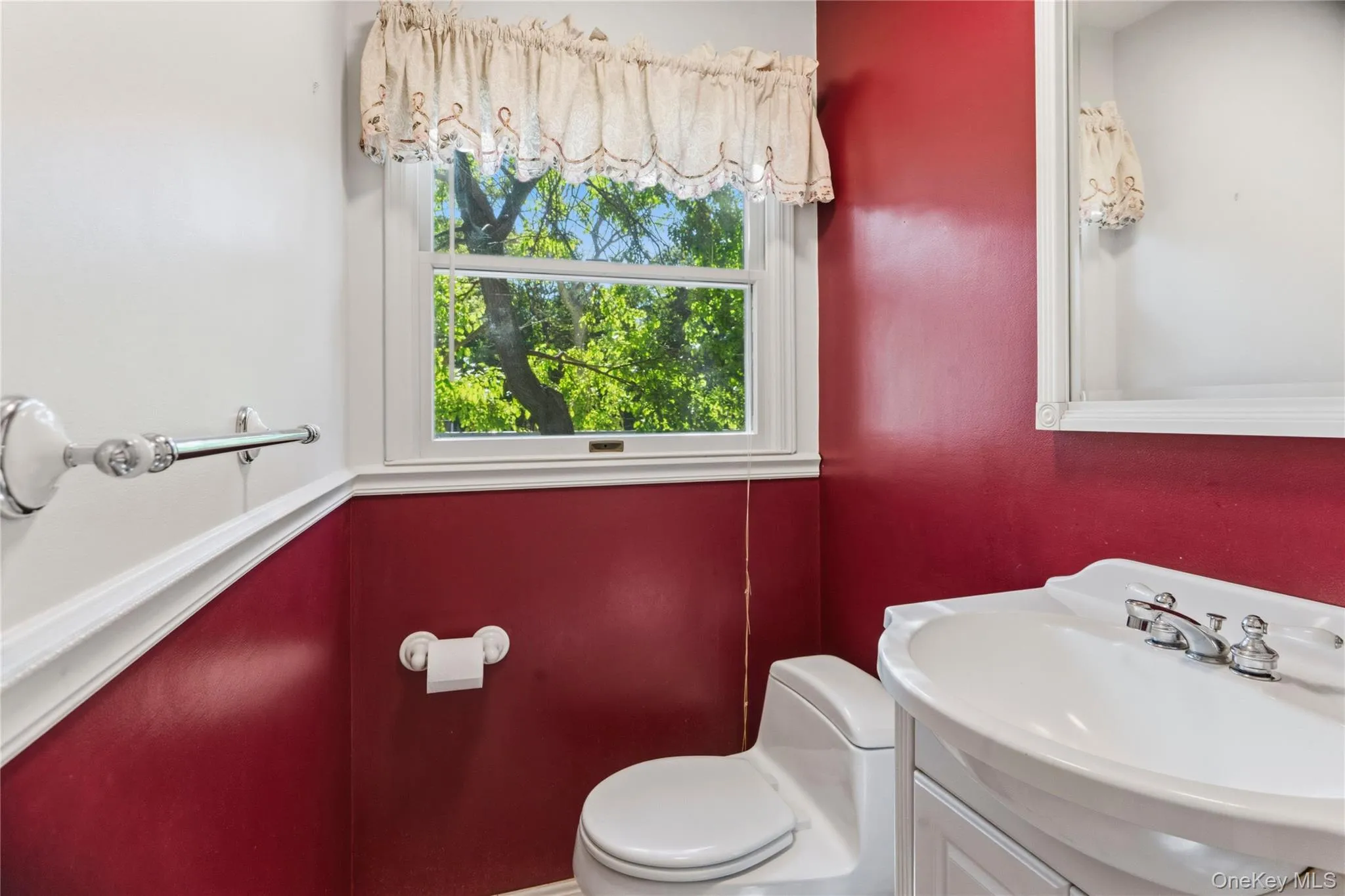 Bathroom featuring a single window, white vanity with integrated sink, chrome faucet, and a toilet Bathroom featuring a single window, white vanity with integrated sink, chrome faucet, and a toilet