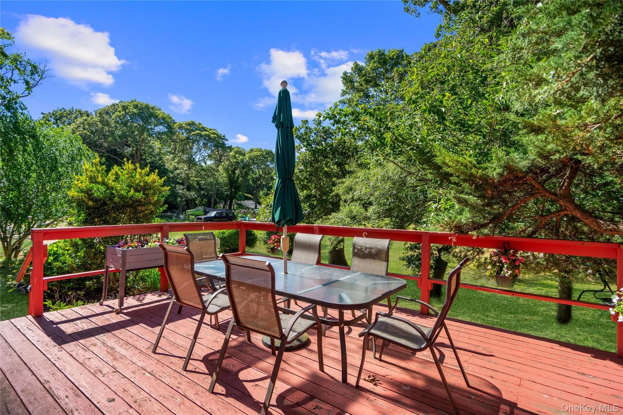 Spacious wooden deck with vibrant red railings, surrounded by lush green foliage Spacious wooden deck with vibrant red railings, surrounded by lush green foliage
