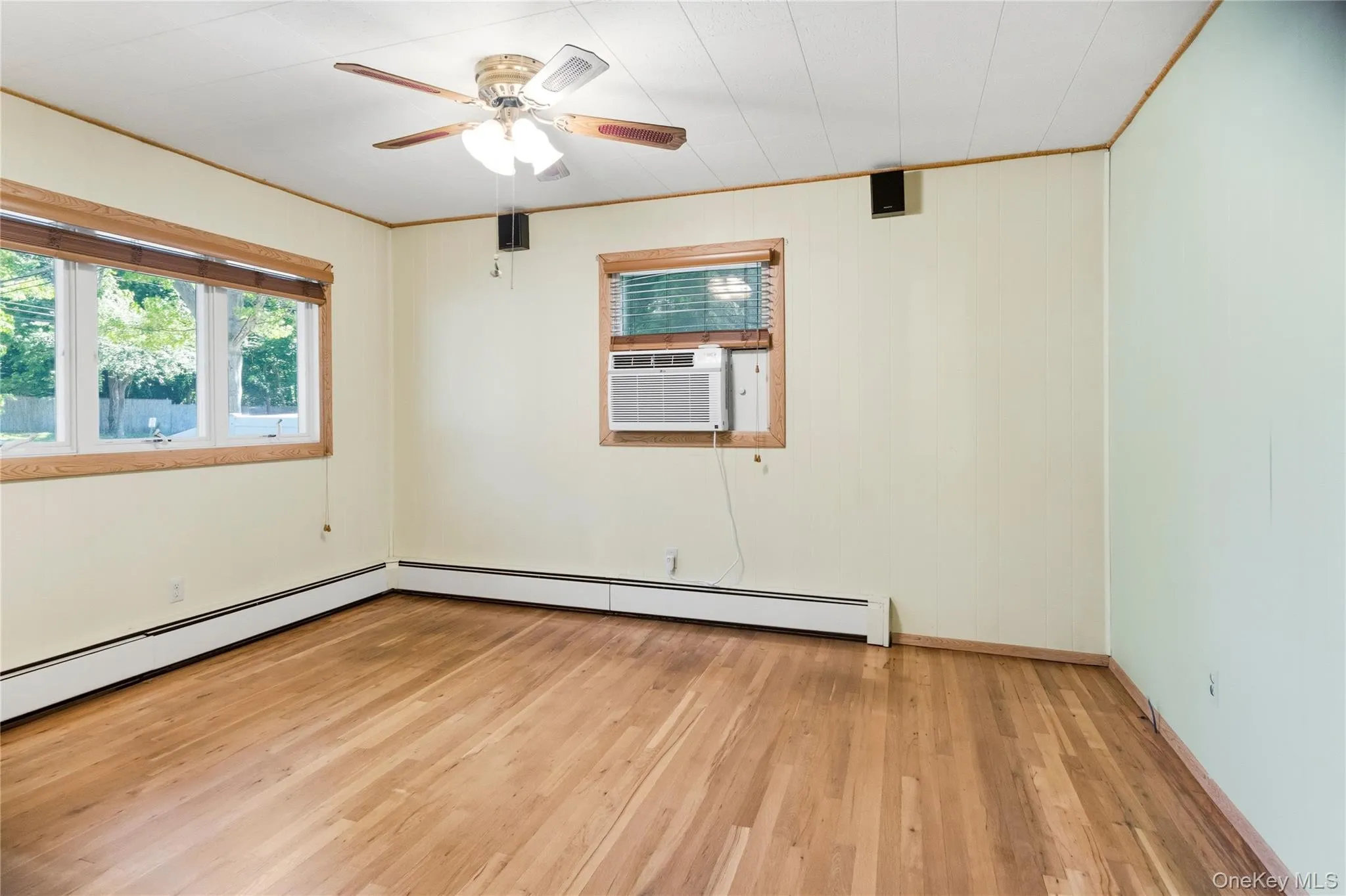 Room with wood-finish flooring, two windows with wood trim, and a ceiling fan Room with wood-finish flooring, two windows with wood trim, and a ceiling fan