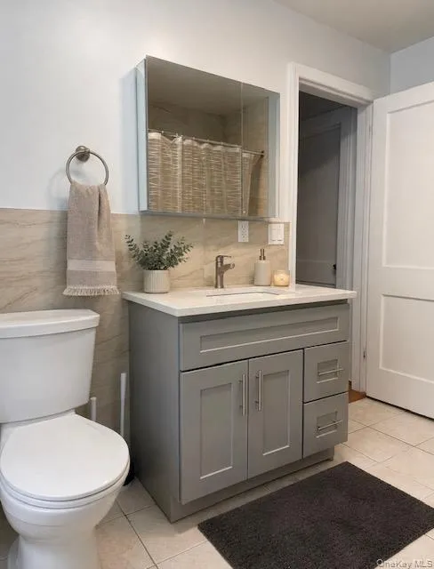 Bathroom featuring a gray shaker-style vanity with white countertop, integrated sink, and brushed nickel faucet Bathroom featuring a gray shaker-style vanity with white countertop, integrated sink, and brushed nickel faucet