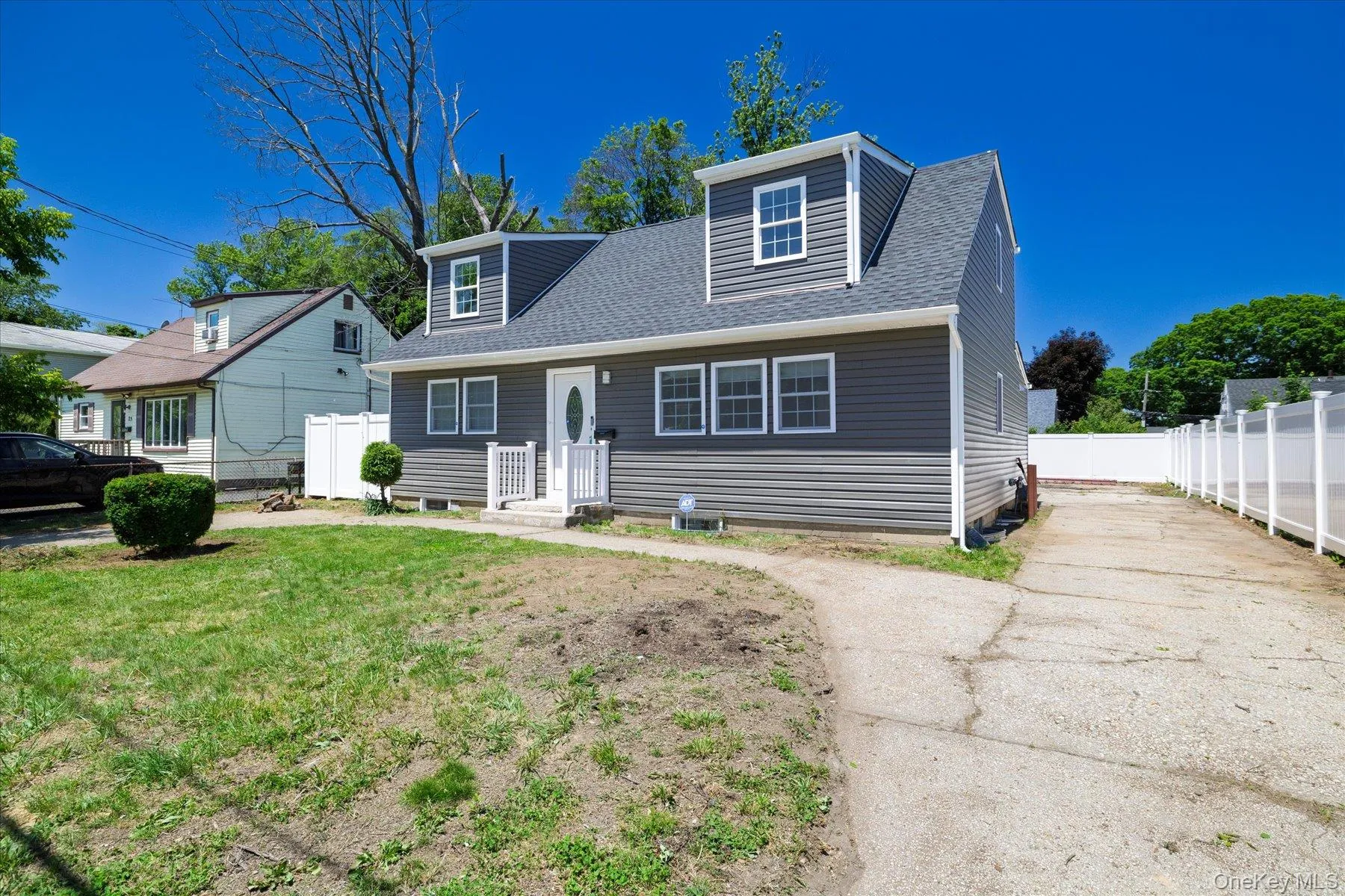 Dormered home featuring gray horizontal siding, white trim, a dark gray shingle roof, and a white front entry door with an oval glass insert Dormered home featuring gray horizontal siding, white trim, a dark gray shingle roof, and a white front entry door with an oval glass insert