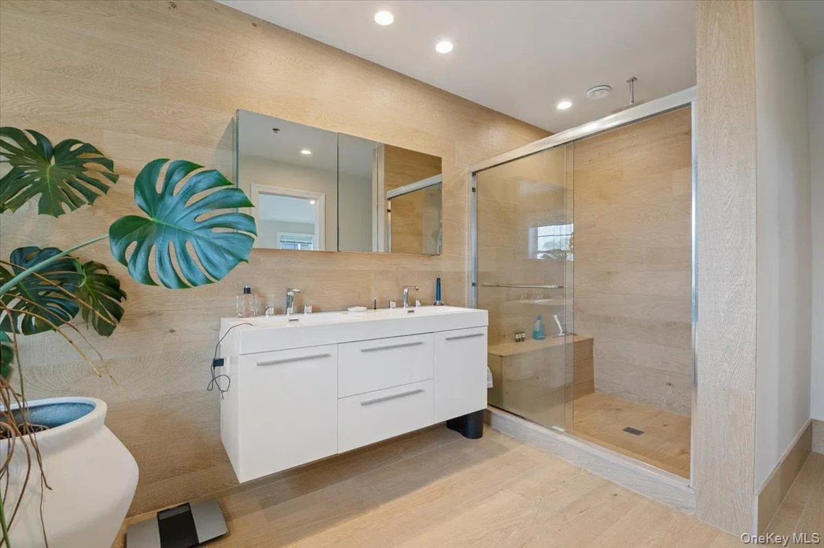 Bathroom featuring wood finished floors, a shower stall, double vanity, and recessed lighting Bathroom featuring wood finished floors, a shower stall, double vanity, and recessed lighting