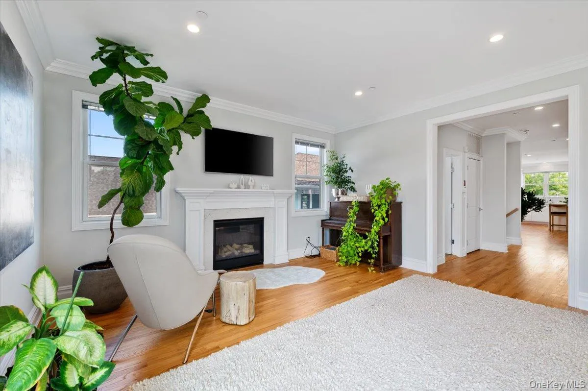 Living room with wood finished floors, a fireplace, crown molding, and recessed lighting Living room with wood finished floors, a fireplace, crown molding, and recessed lighting