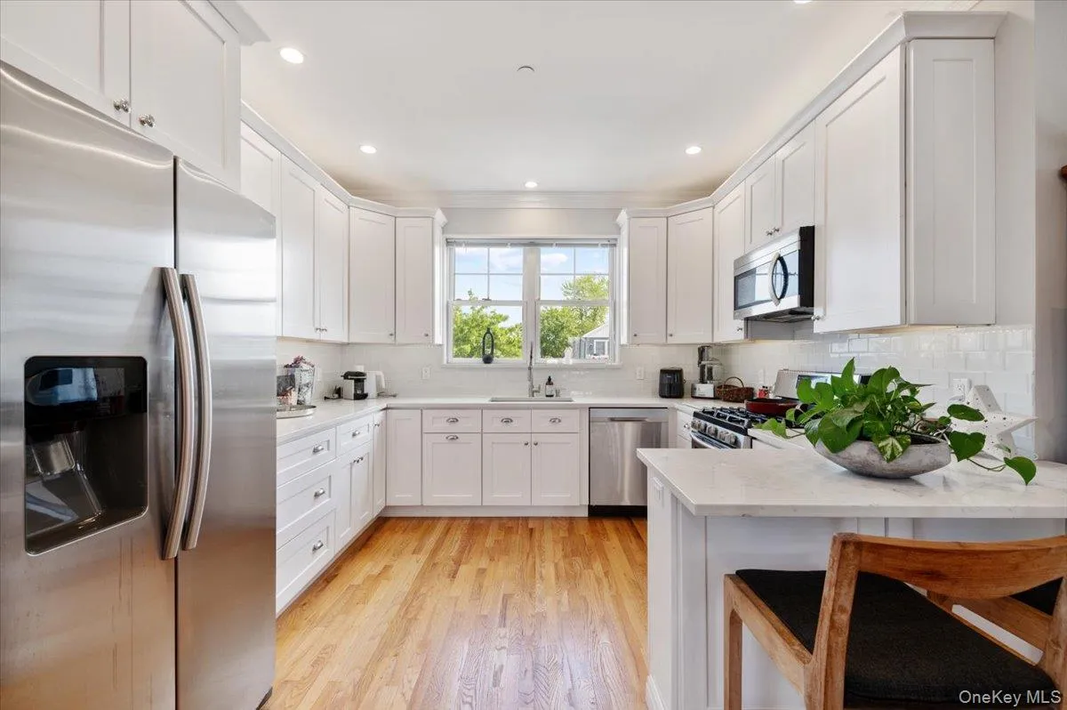 Kitchen with stainless steel appliances, light countertops, a peninsula, decorative backsplash, and recessed lighting Kitchen with stainless steel appliances, light countertops, a peninsula, decorative backsplash, and recessed lighting