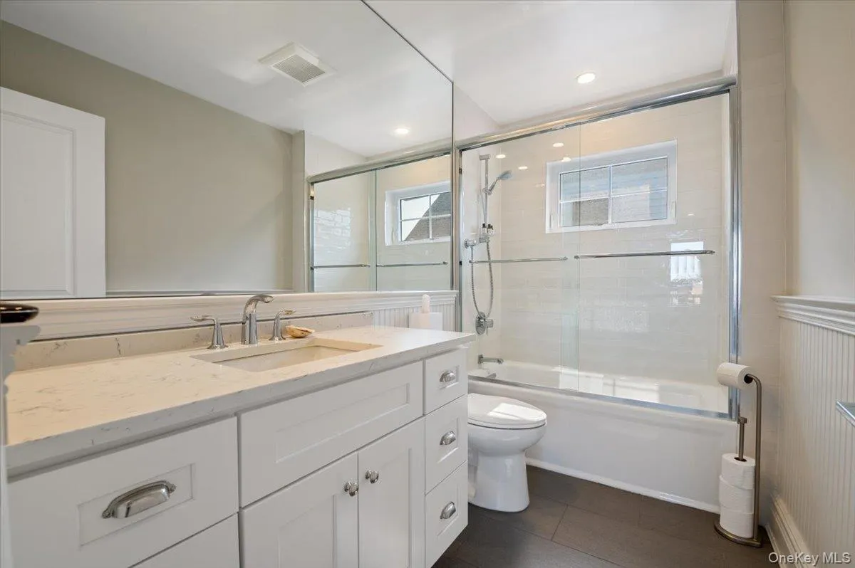 Bathroom with vanity, enclosed tub / shower combo, and tile patterned flooring Bathroom with vanity, enclosed tub / shower combo, and tile patterned flooring