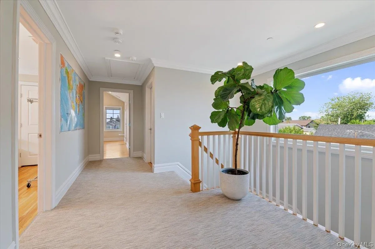 Hall with attic access, ornamental molding, recessed lighting, light colored carpet, and an upstairs landing Hall with attic access, ornamental molding, recessed lighting, light colored carpet, and an upstairs landing