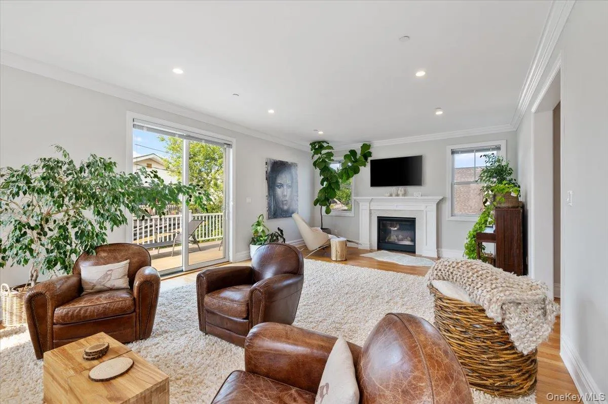 Living room featuring crown molding, light wood-style flooring, a fireplace with flush hearth, and recessed lighting Living room featuring crown molding, light wood-style flooring, a fireplace with flush hearth, and recessed lighting