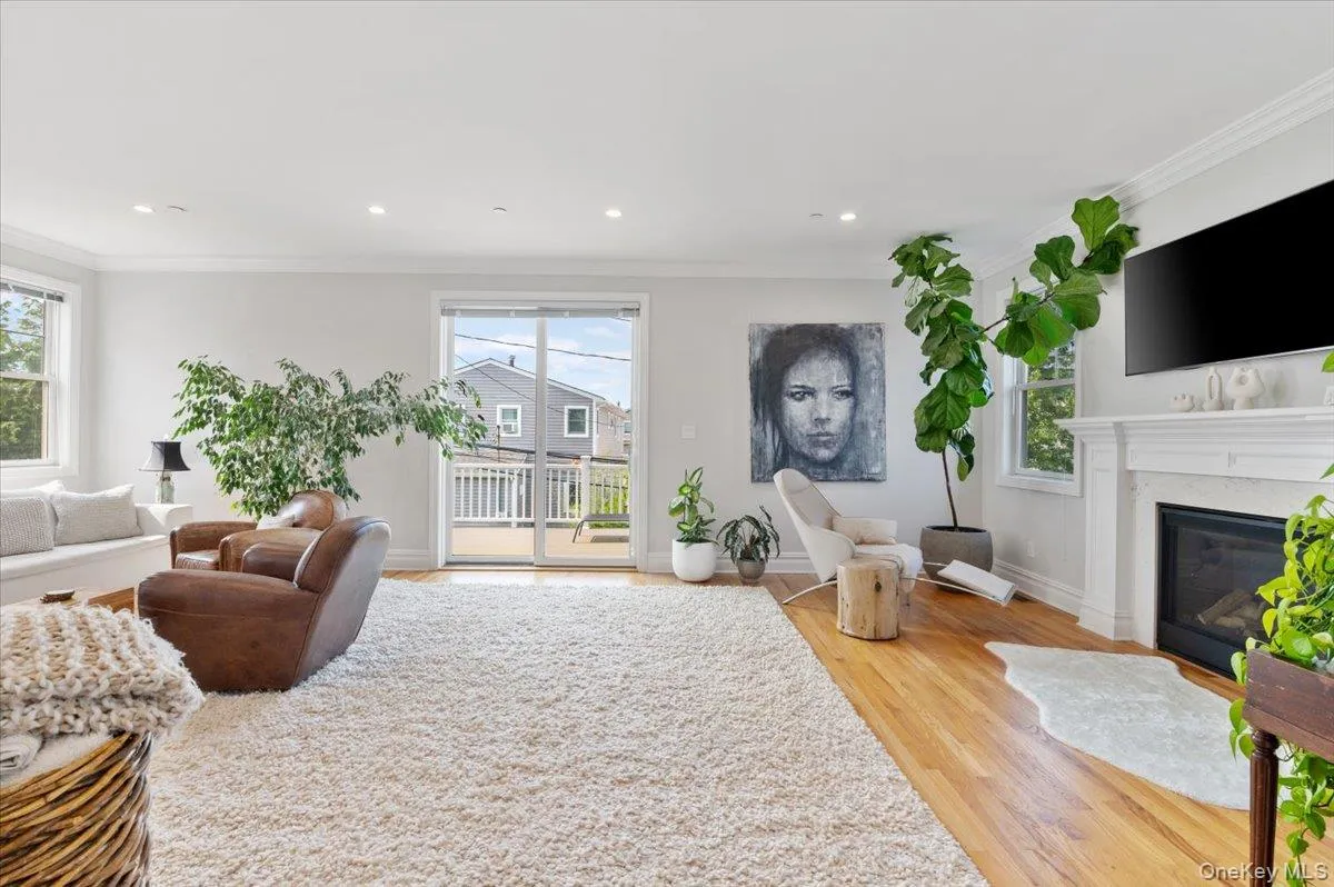 Living area featuring plenty of natural light, crown molding, wood finished floors, a premium fireplace, and recessed lighting Living area featuring plenty of natural light, crown molding, wood finished floors, a premium fireplace, and recessed lighting