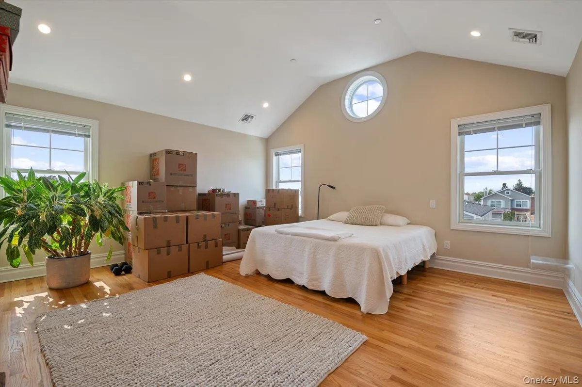 Bedroom with light wood-style floors, vaulted ceiling, and recessed lighting Bedroom with light wood-style floors, vaulted ceiling, and recessed lighting