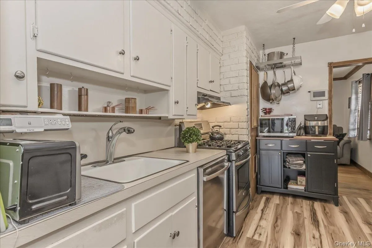 Kitchen featuring white cabinetry, a built-in sink, stainless steel appliances, and wood-finish flooring Kitchen featuring white cabinetry, a built-in sink, stainless steel appliances, and wood-finish flooring