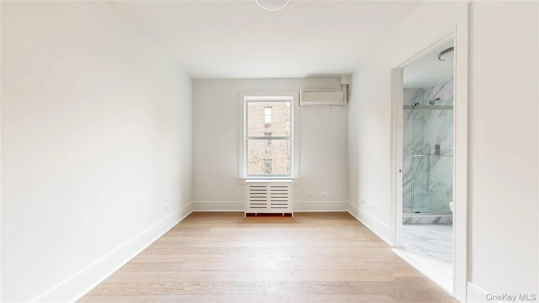 Bright bedroom featuring two double-hung windows, wood-finish flooring, and white painted walls Bright bedroom featuring two double-hung windows, wood-finish flooring, and white painted walls