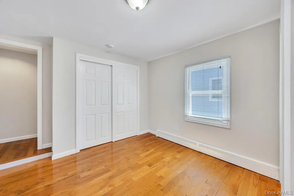 Room featuring wood-finish flooring, light grey walls, and white baseboards Room featuring wood-finish flooring, light grey walls, and white baseboards