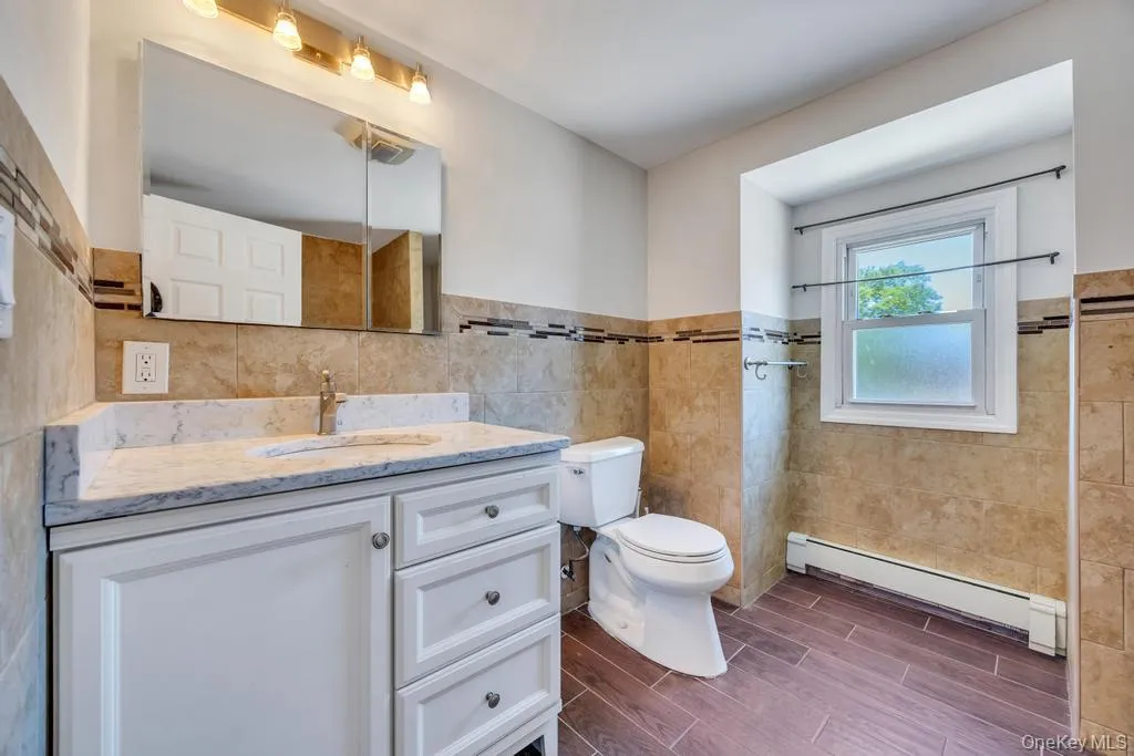 Bathroom featuring a white vanity with a light-colored countertop, an integrated sink, and an overhead medicine cabinet with task lighting Bathroom featuring a white vanity with a light-colored countertop, an integrated sink, and an overhead medicine cabinet with task lighting