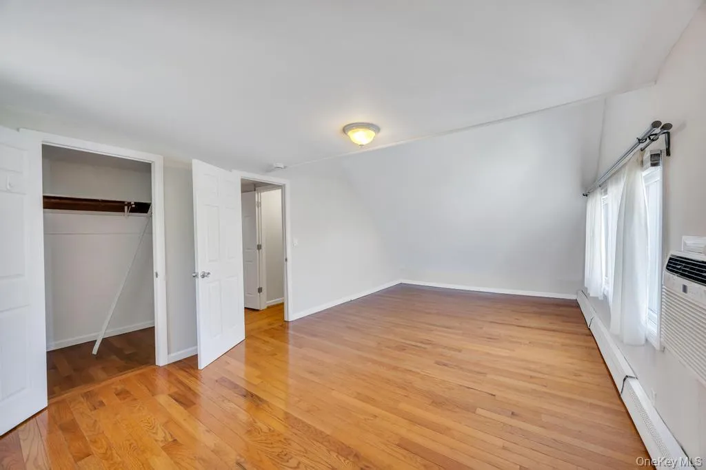 Bright interior space featuring wood-finish flooring, white walls, and a sloped ceiling Bright interior space featuring wood-finish flooring, white walls, and a sloped ceiling
