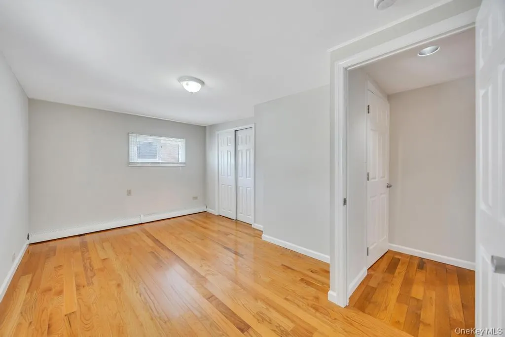 Room featuring wood-finish flooring, light grey walls, and white trim Room featuring wood-finish flooring, light grey walls, and white trim