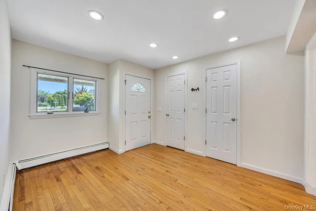 Hardwood flooring throughout, multiple recessed lighting fixtures, and a glass-paneled entry door Hardwood flooring throughout, multiple recessed lighting fixtures, and a glass-paneled entry door