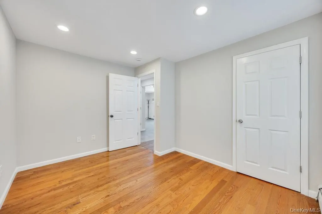 Interior room featuring wood-finish flooring, light grey walls, white trim, and recessed ceiling lighting Interior room featuring wood-finish flooring, light grey walls, white trim, and recessed ceiling lighting