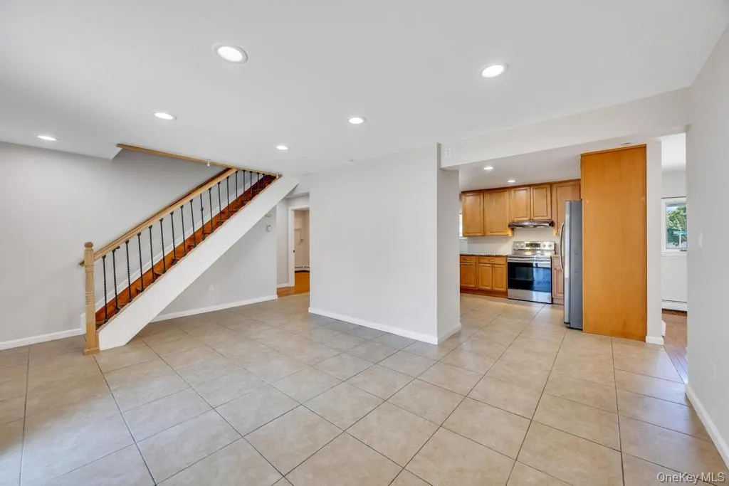 Open-concept living area featuring neutral wall tones, recessed lighting, and large format tile flooring Open-concept living area featuring neutral wall tones, recessed lighting, and large format tile flooring