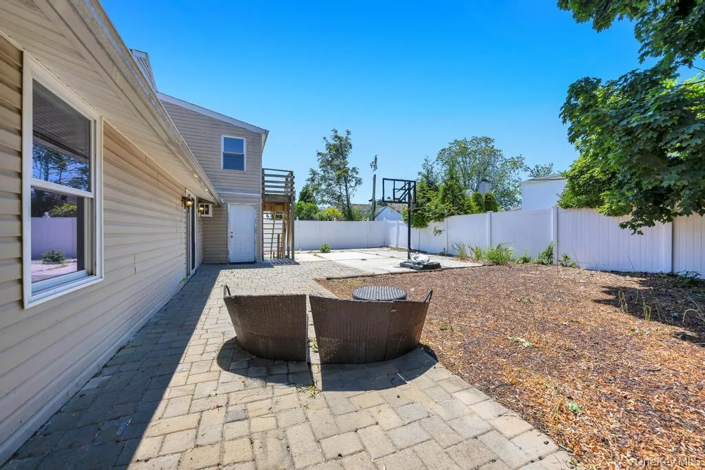 Spacious rear yard featuring a paver patio, separate concrete pad, and full privacy fencing Spacious rear yard featuring a paver patio, separate concrete pad, and full privacy fencing